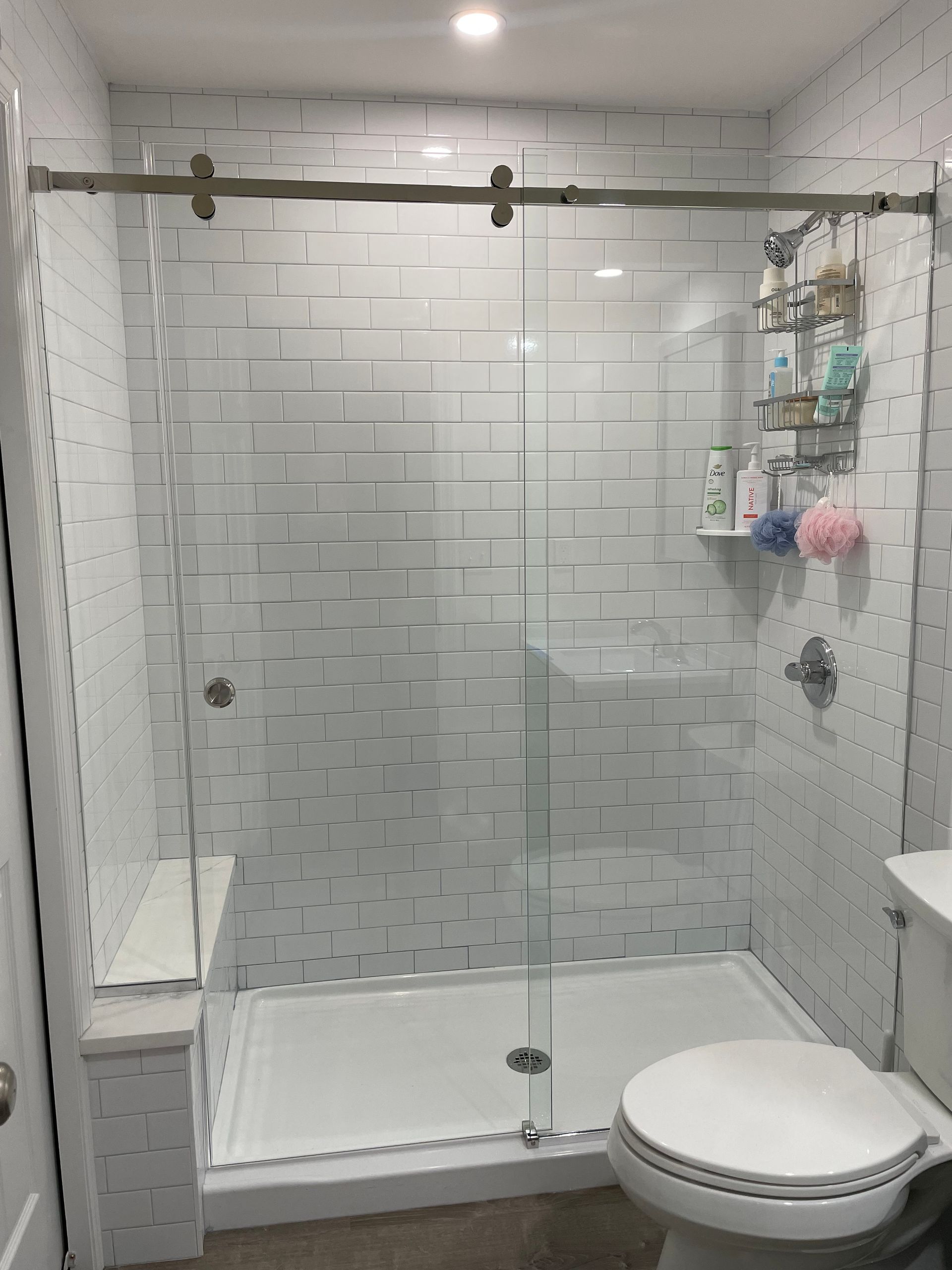 A bathroom with a toilet , shower and sliding glass door.