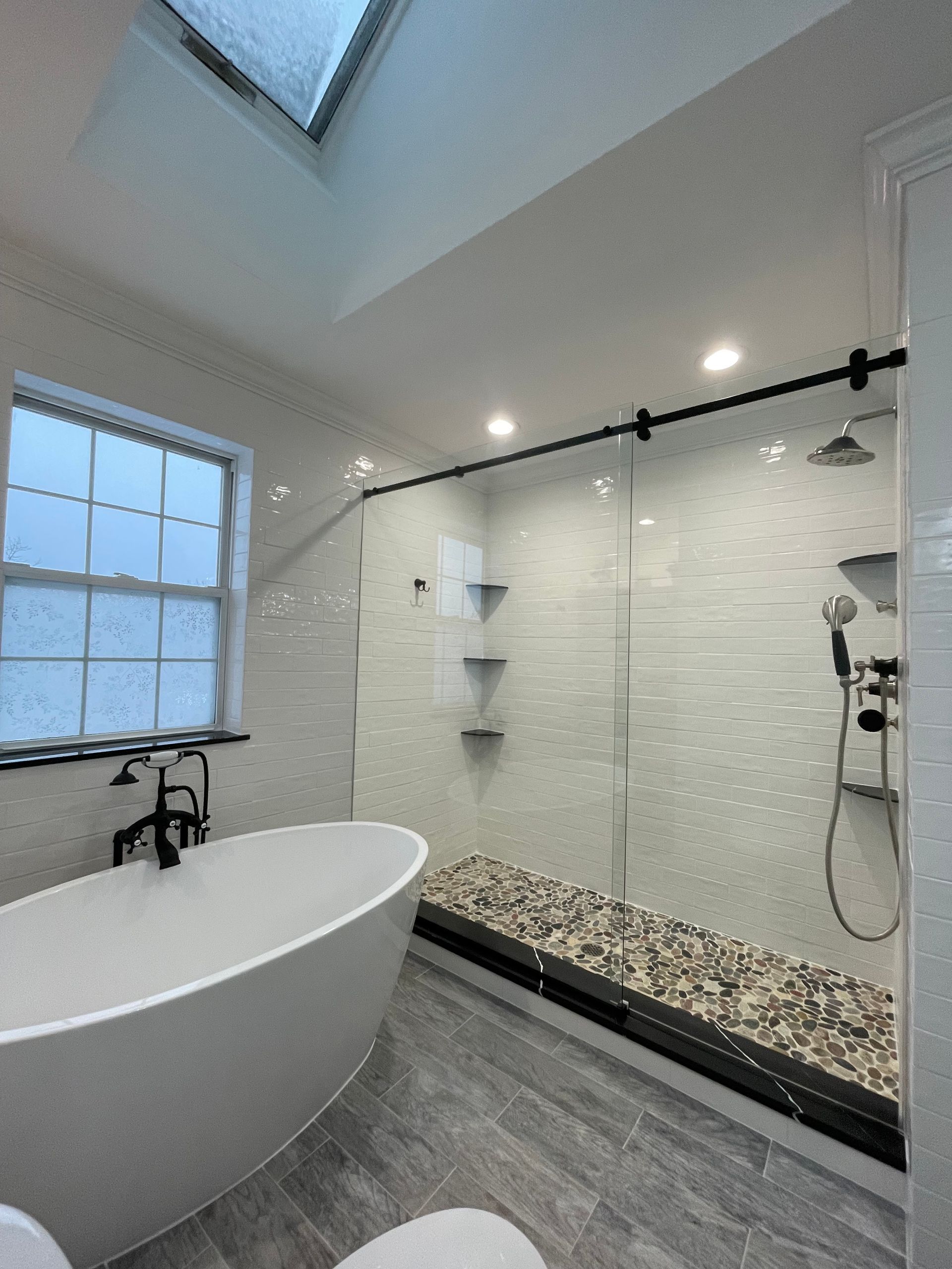 A bathroom with a tub and a shower with a skylight
