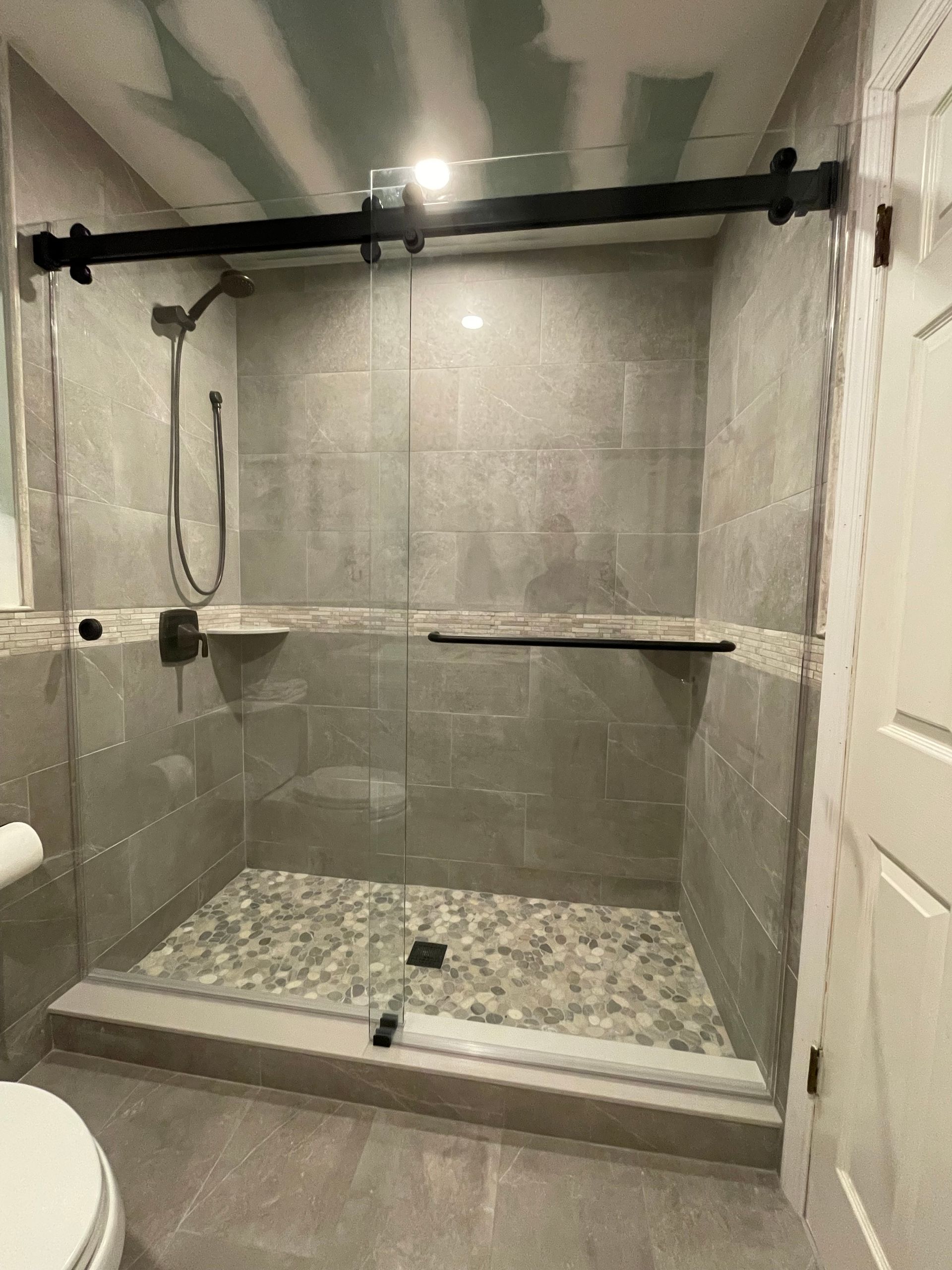 A bathroom with a sliding glass shower door and a toilet.