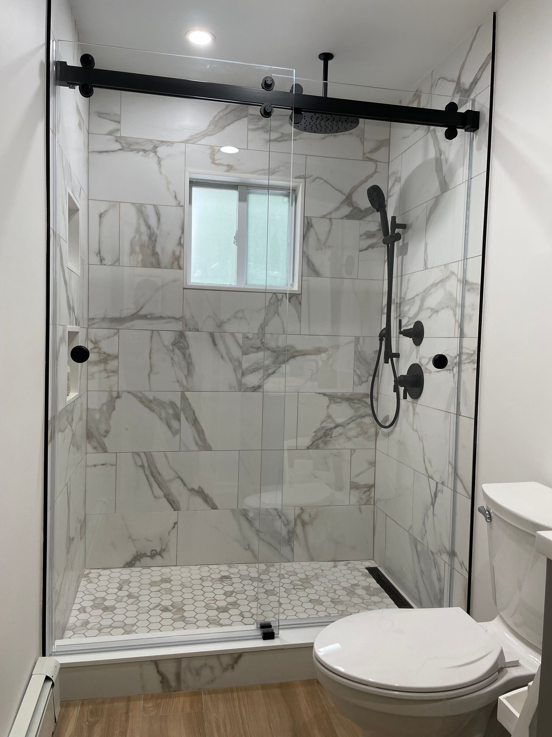 A bathroom with a toilet , shower , and window.