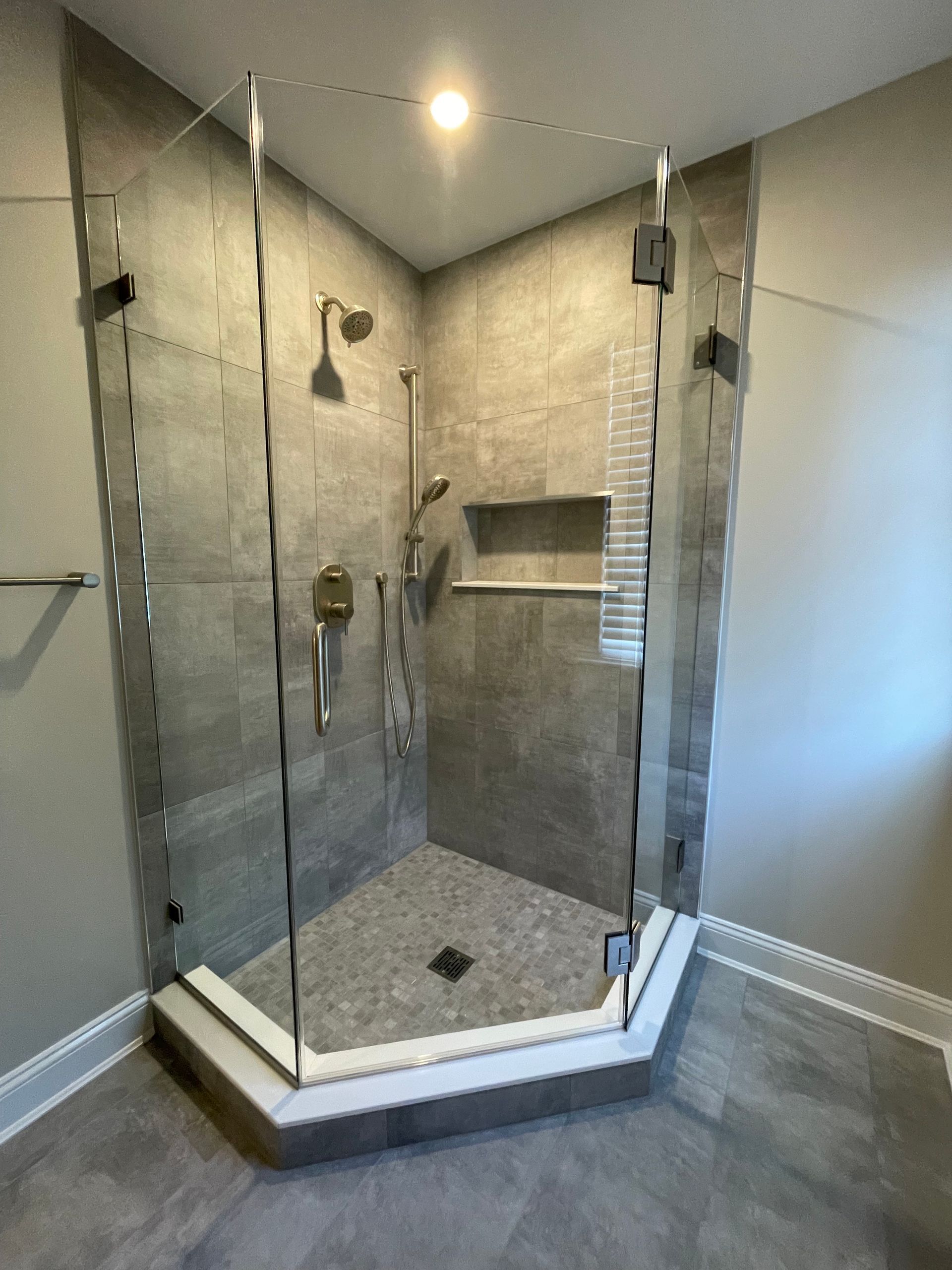A bathroom with a walk in shower with a glass door.