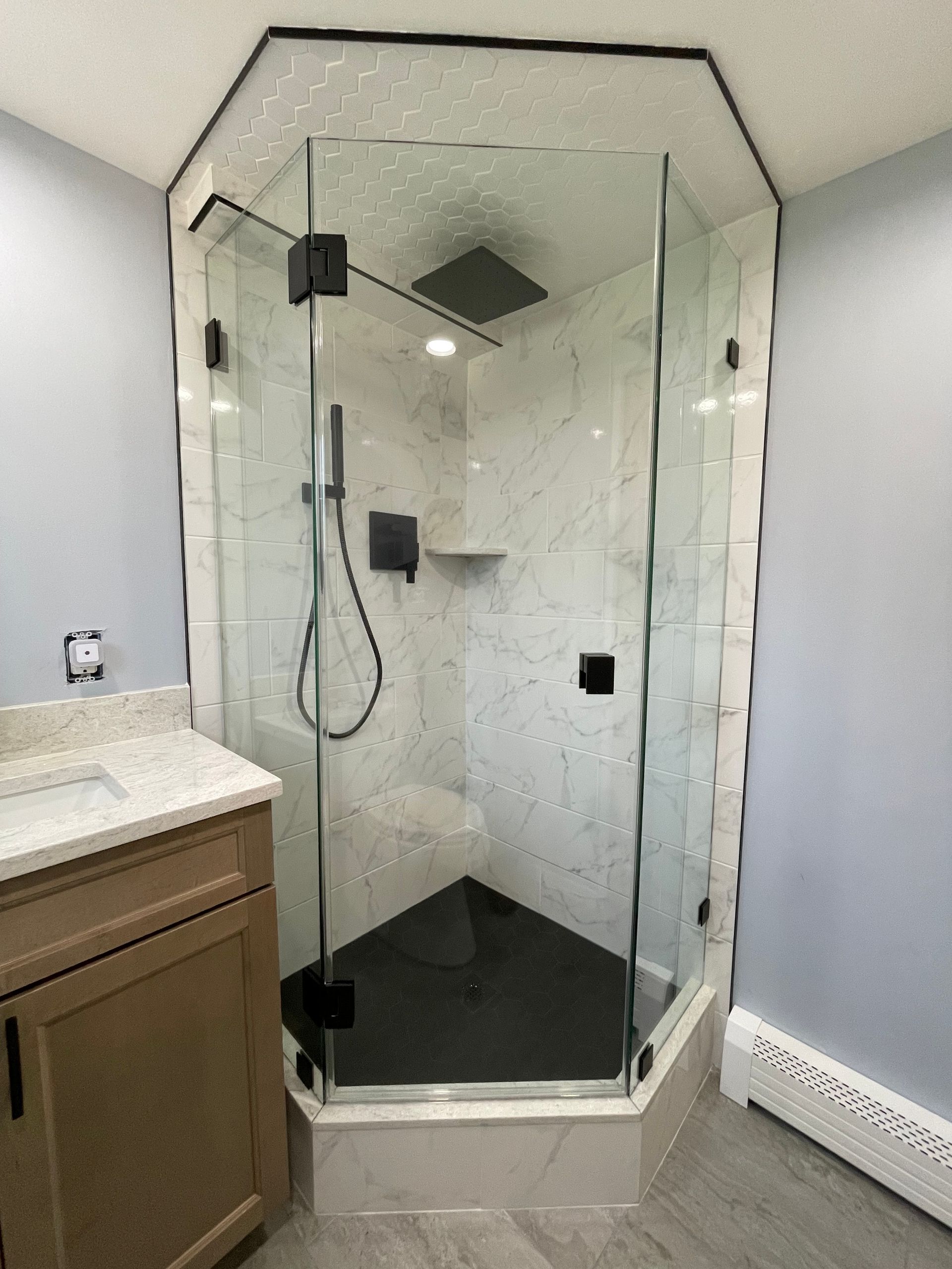 A bathroom with a walk in shower and a sink.
