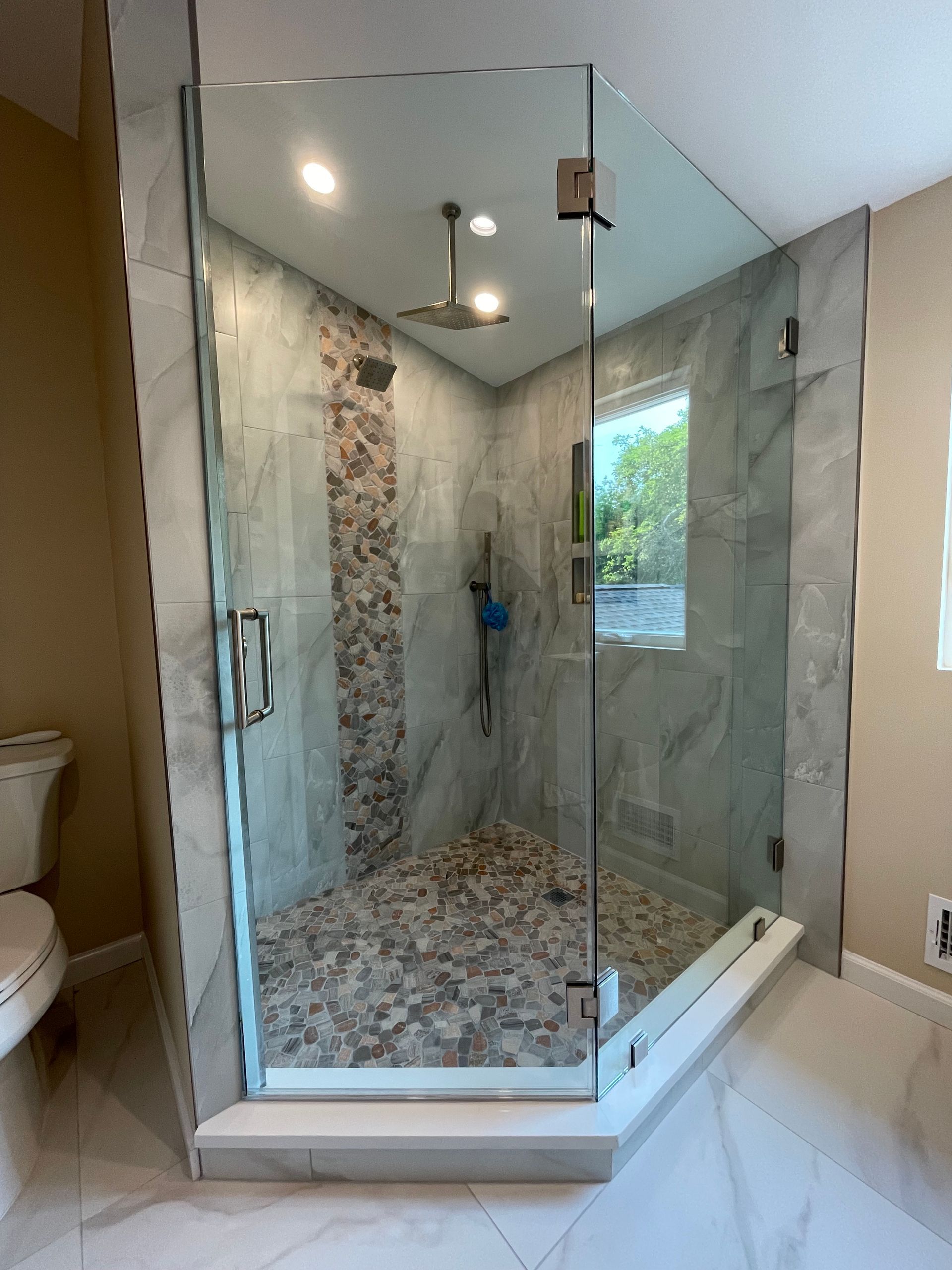 A bathroom with a walk in shower with a glass door.
