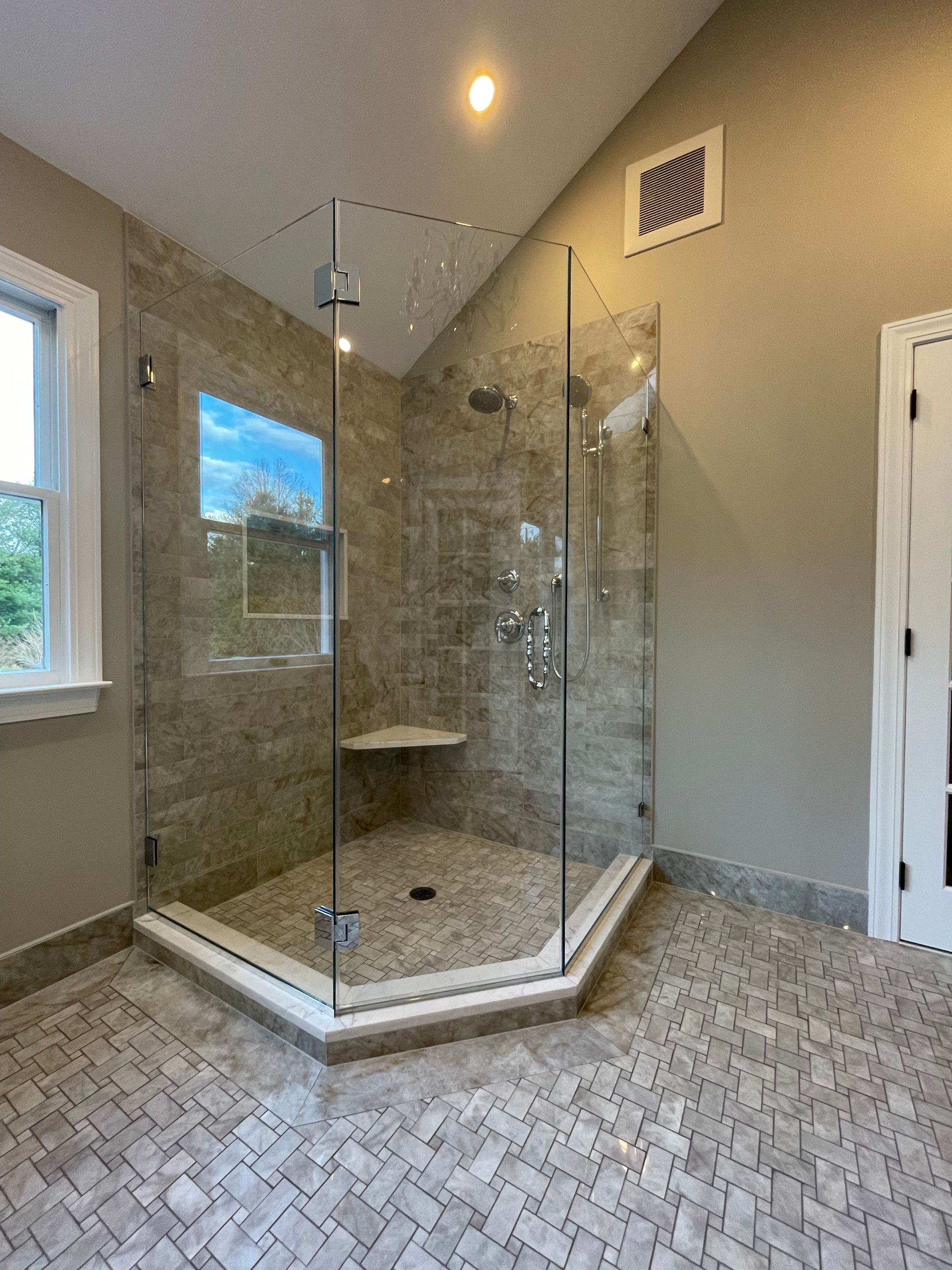 A bathroom with a walk in shower and a window.
