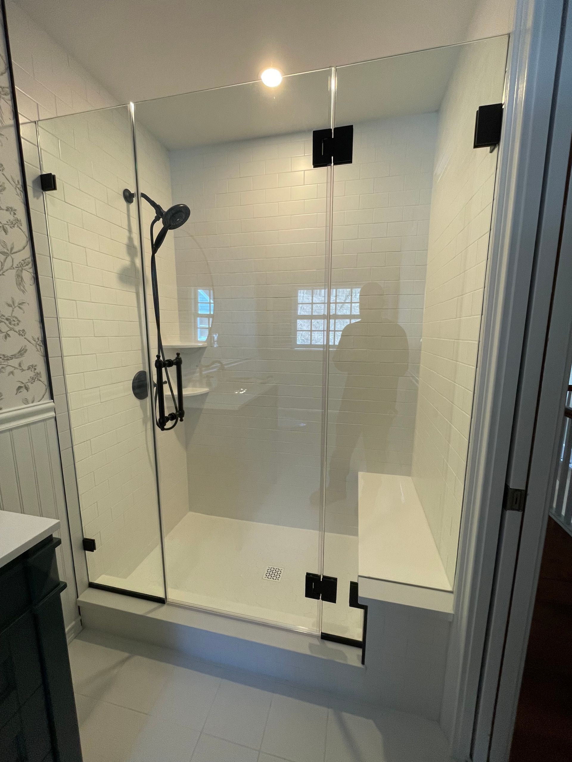 A bathroom with a walk in shower with a glass door.