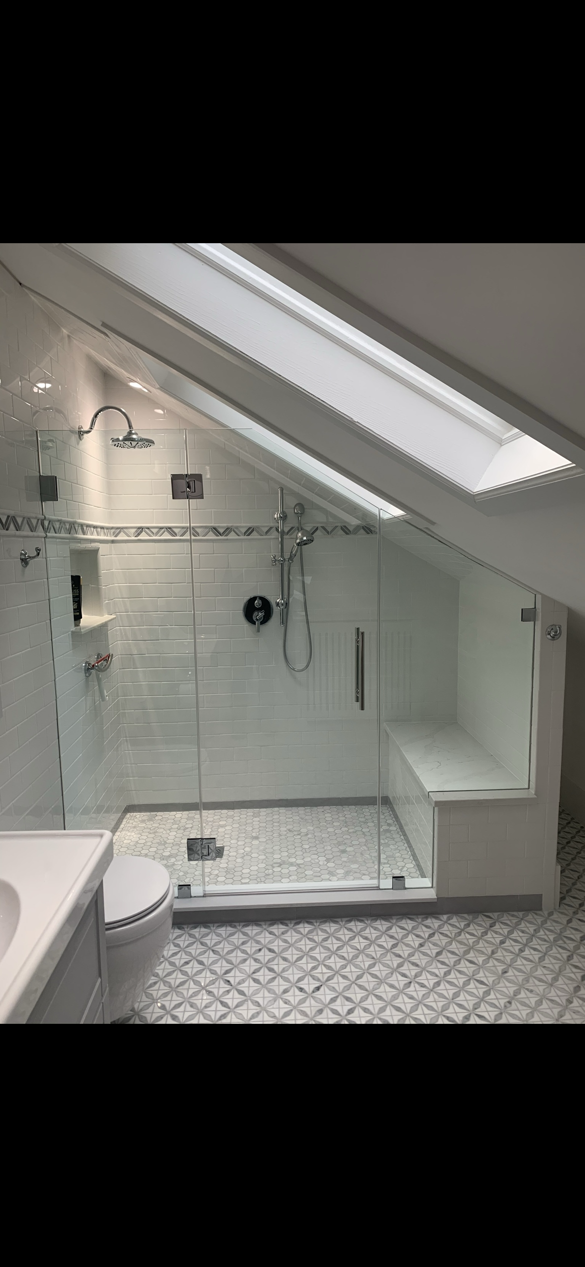 A bathroom with a walk in shower and a skylight.