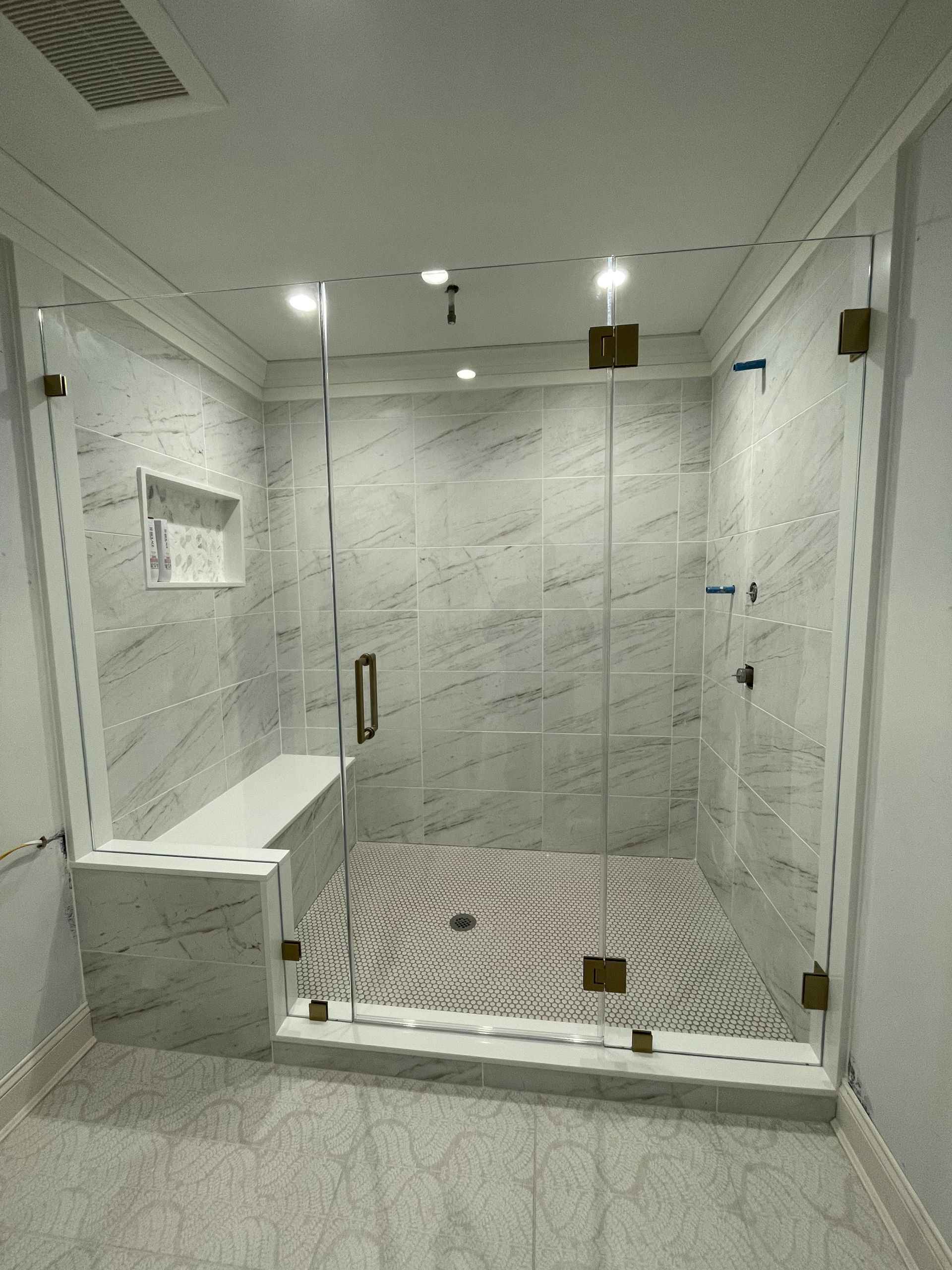 A bathroom with a walk in shower and a bench.