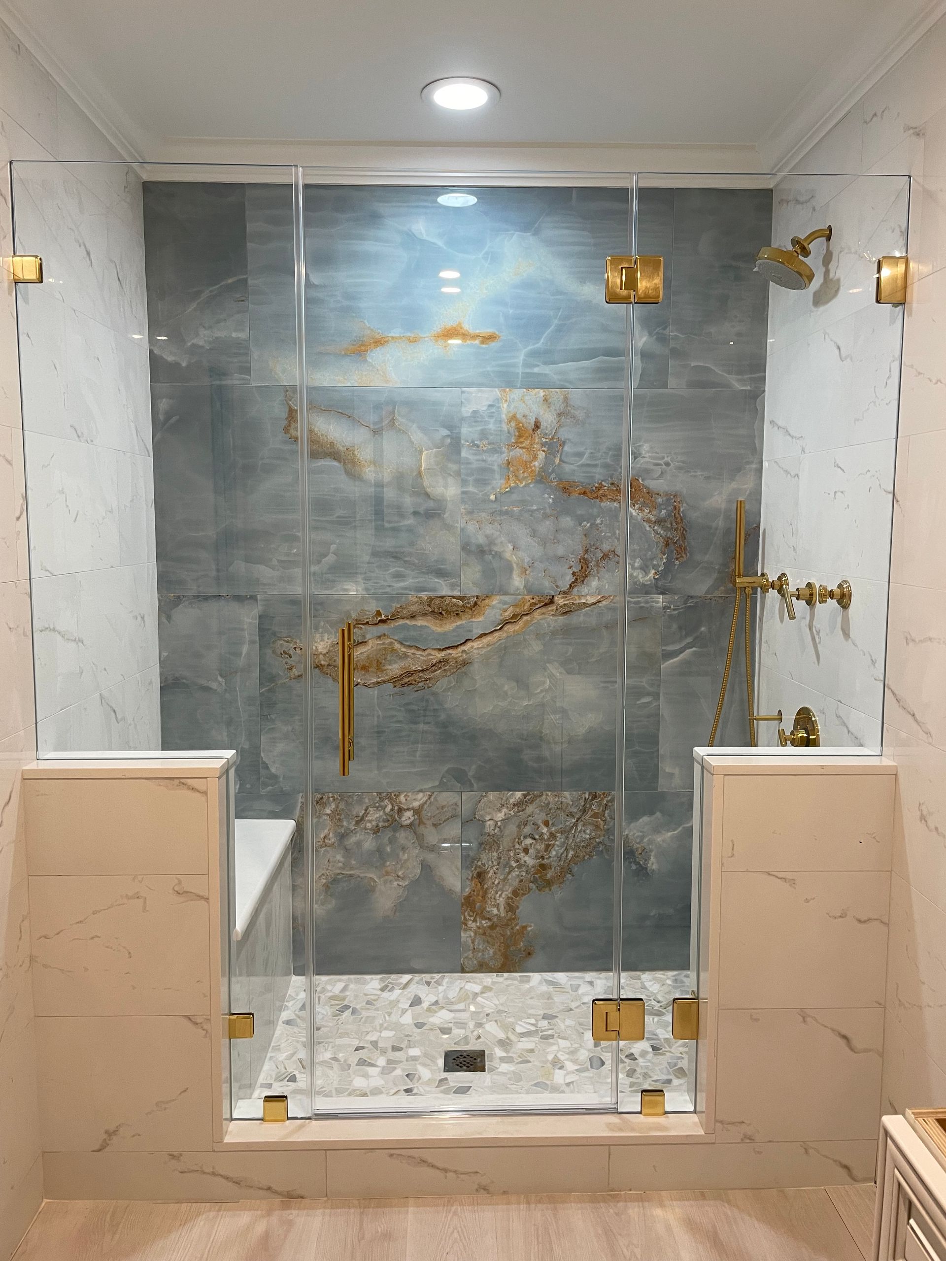 A bathroom with a walk in shower with a glass door.