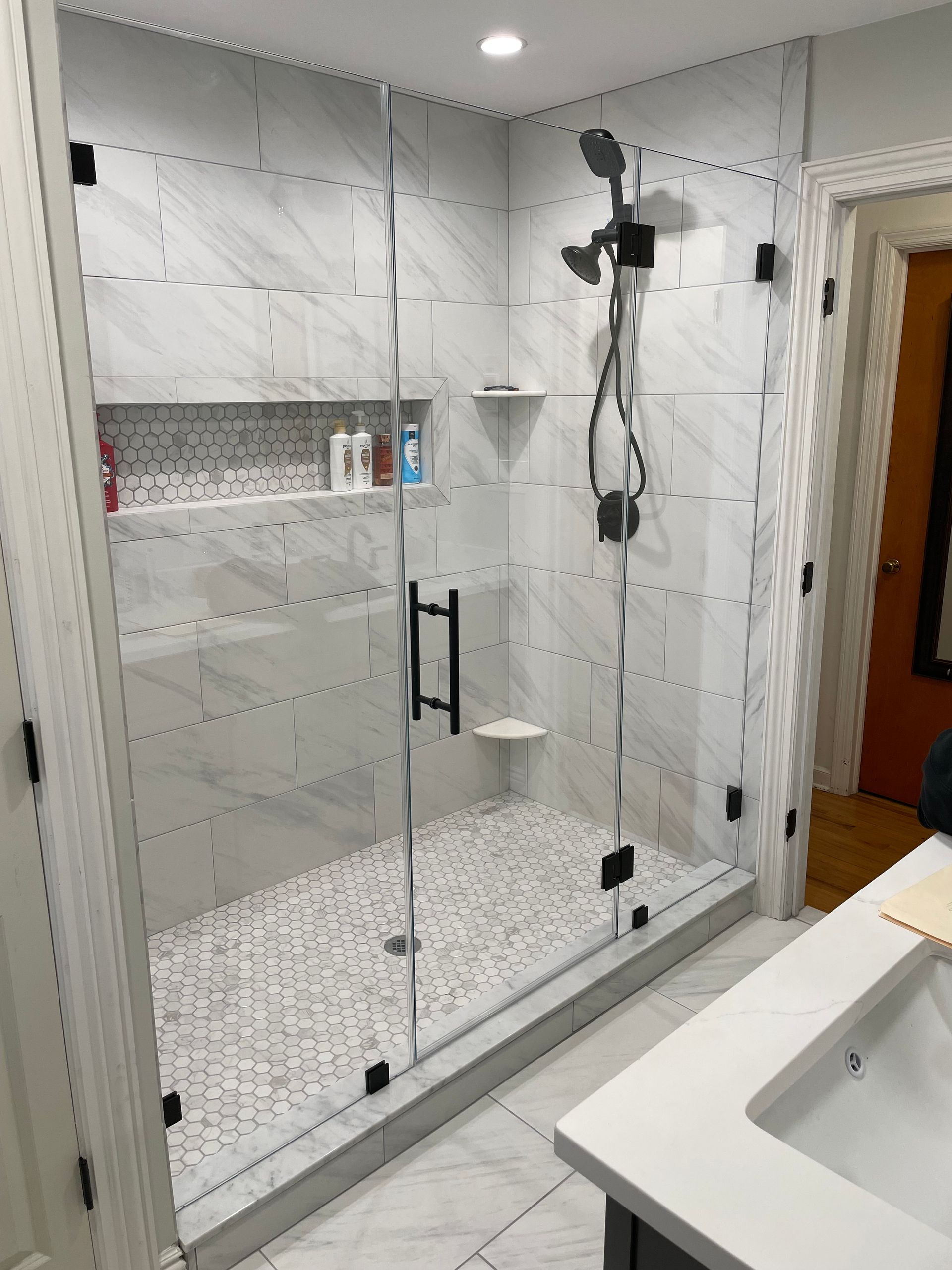 A bathroom with a walk in shower and a sink.