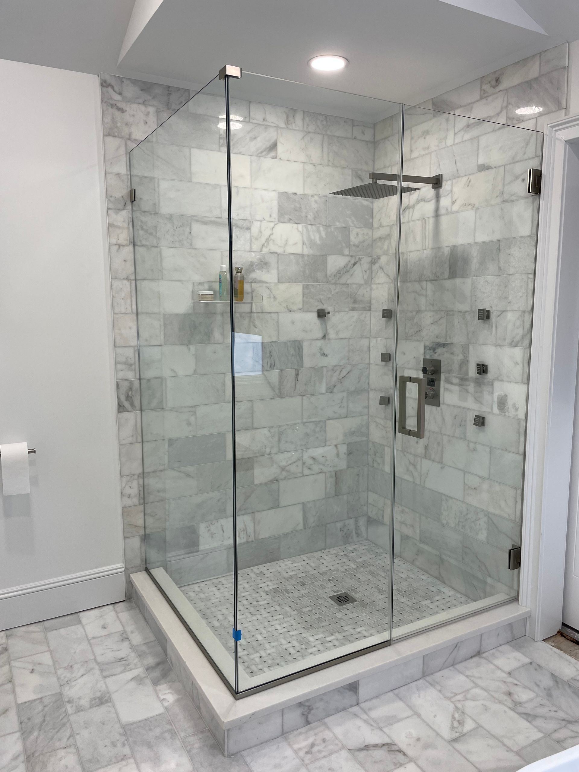 A bathroom with a walk in shower with a glass door.