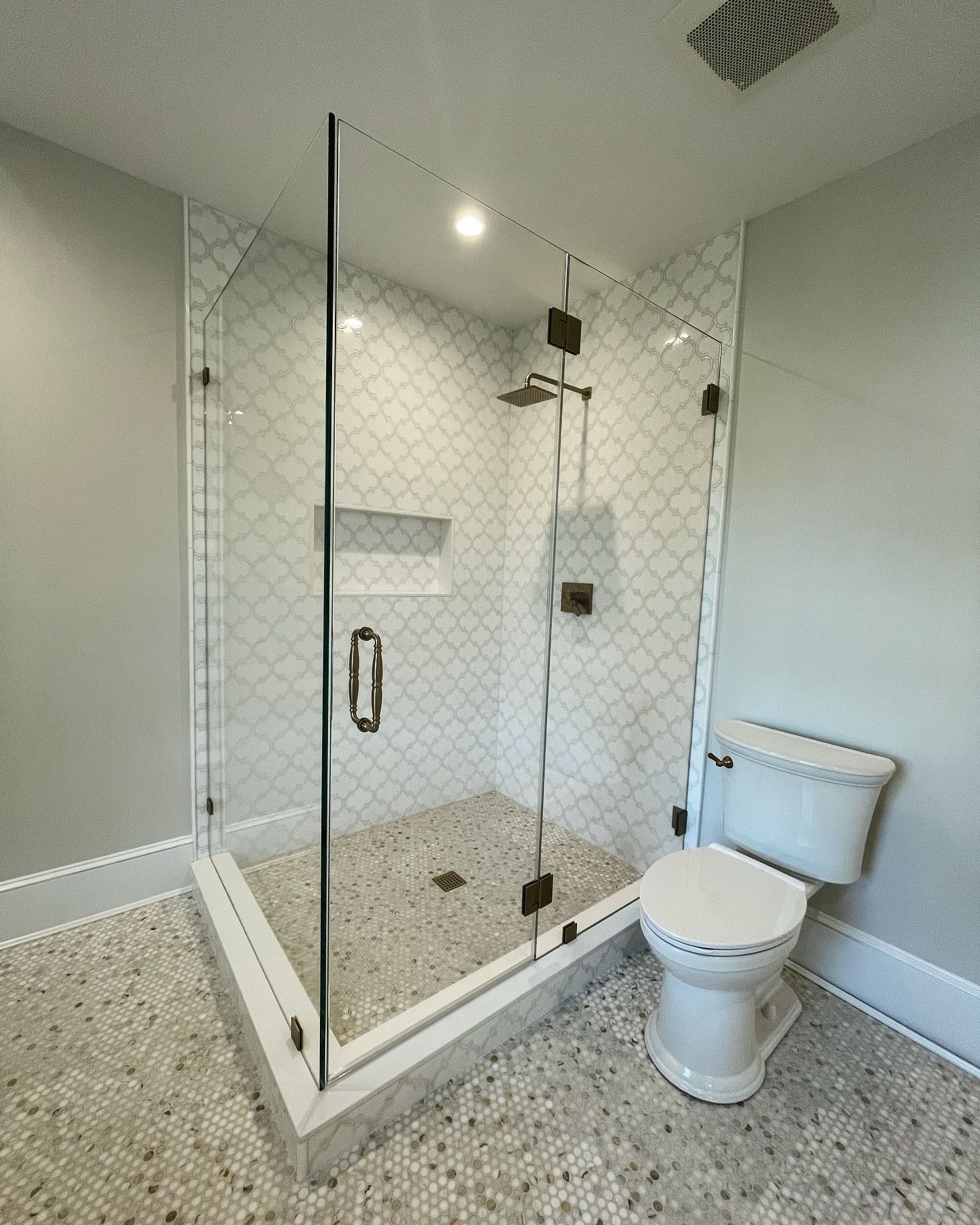 A bathroom with a toilet , shower and glass door.