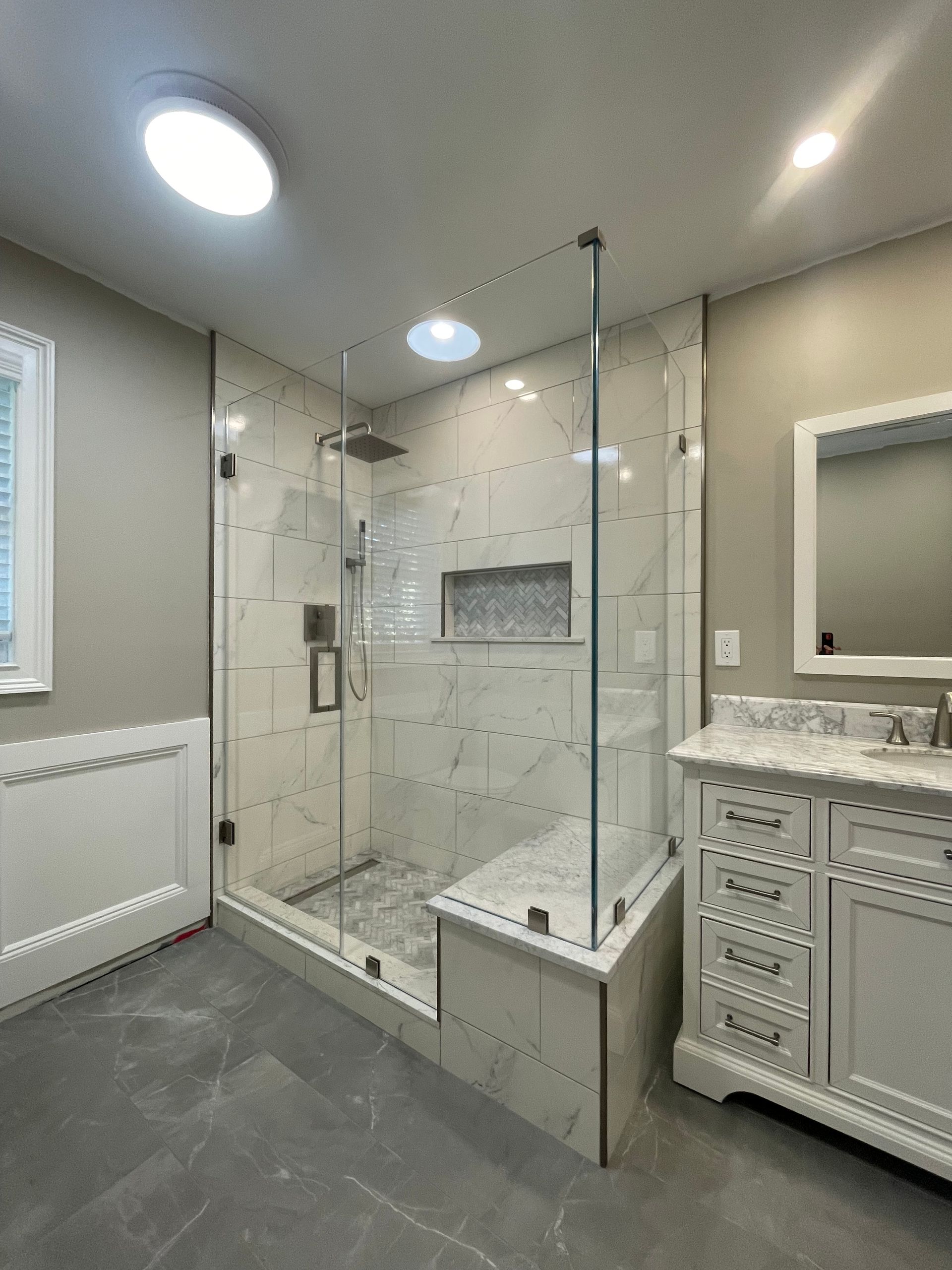 A bathroom with a walk in shower , sink and mirror.