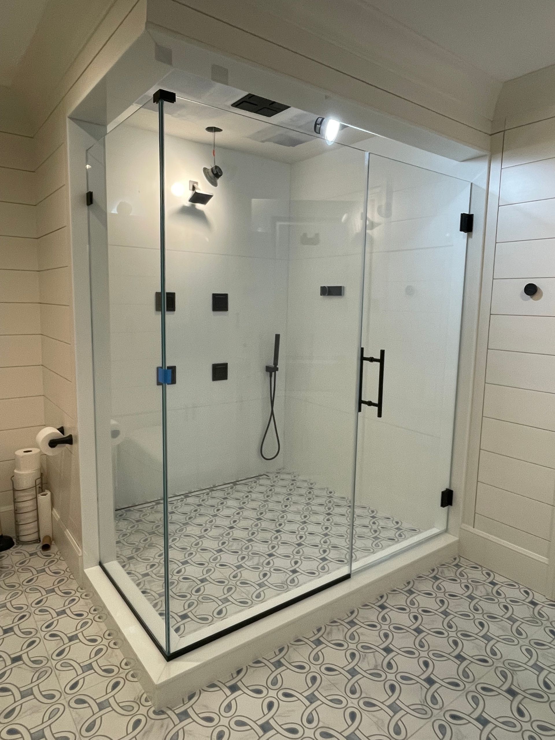 A bathroom with a walk in shower with a glass door