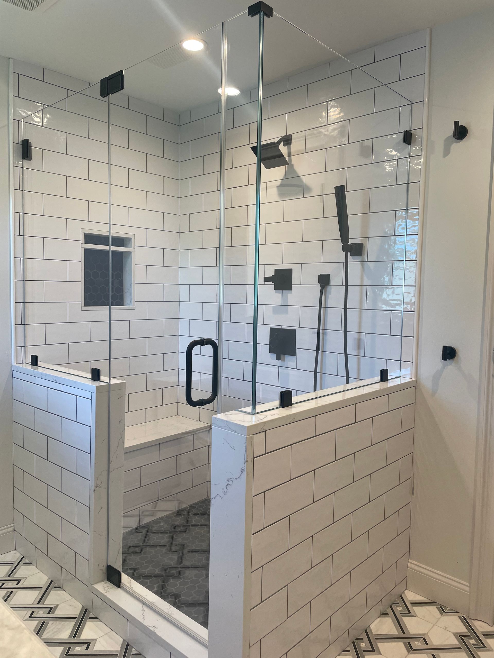A bathroom with white tiles and a walk in shower