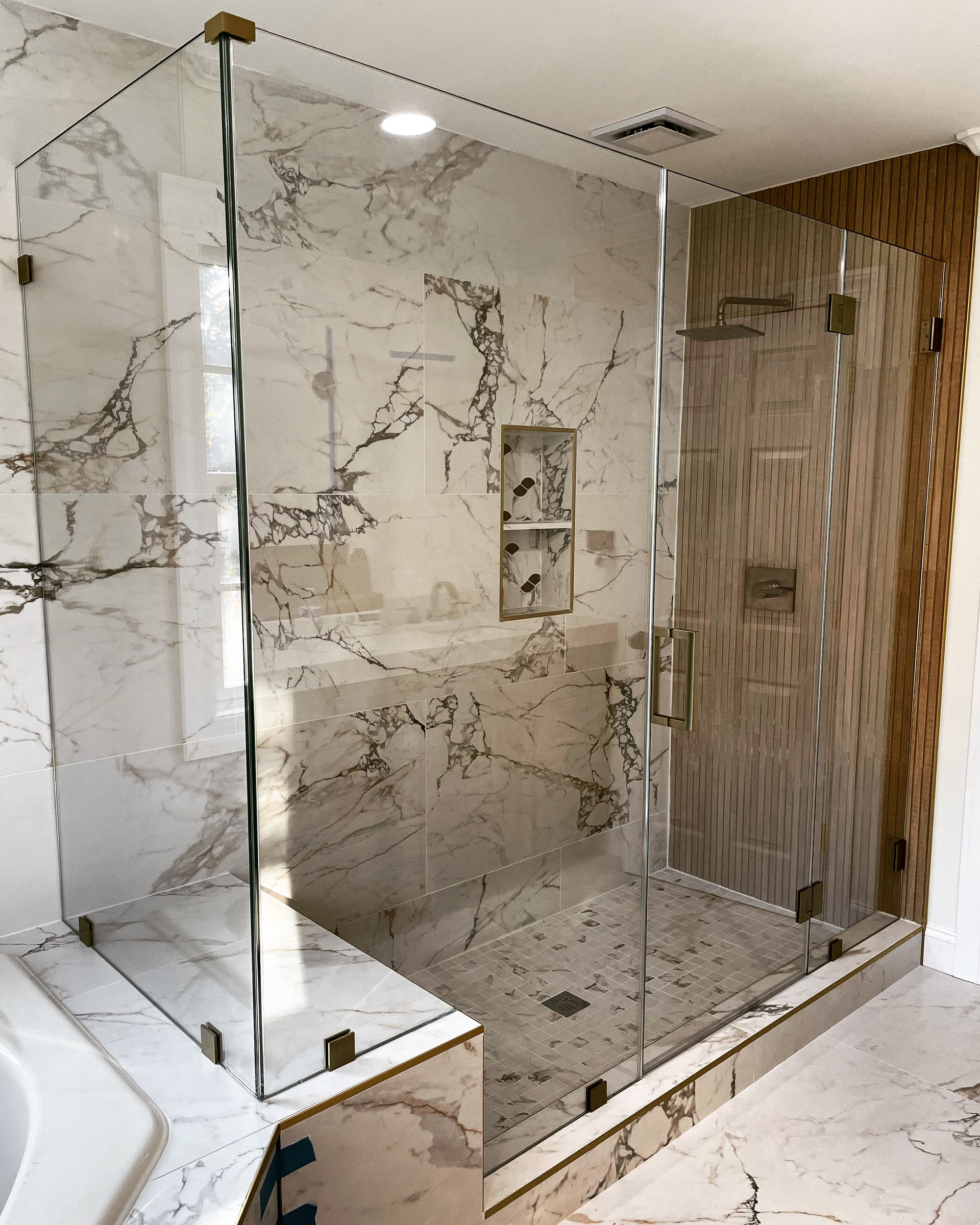 A bathroom with marble tiles and a glass shower door