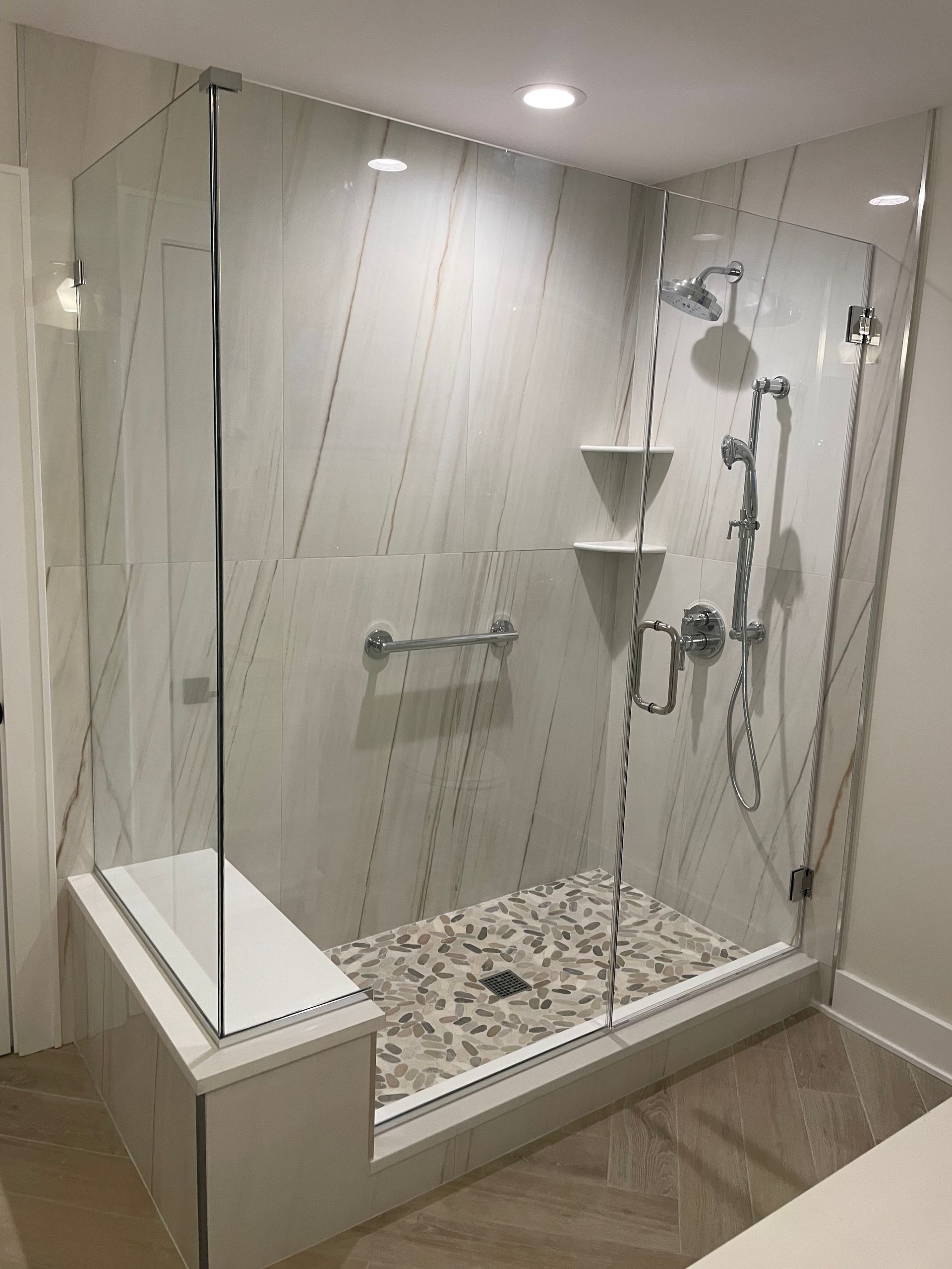A bathroom with a walk in shower with a glass door.