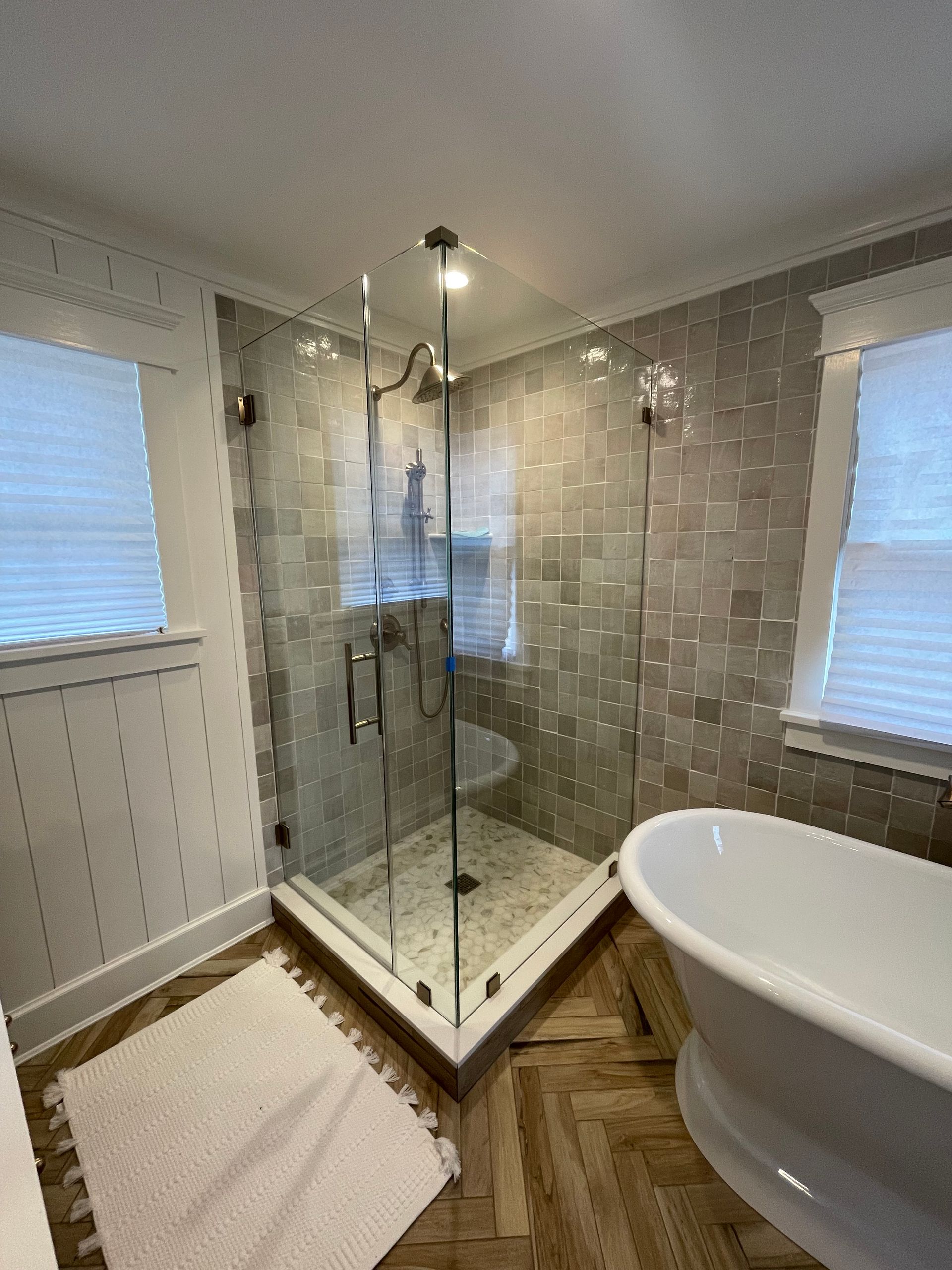 A bathroom with a tub , shower , and window.