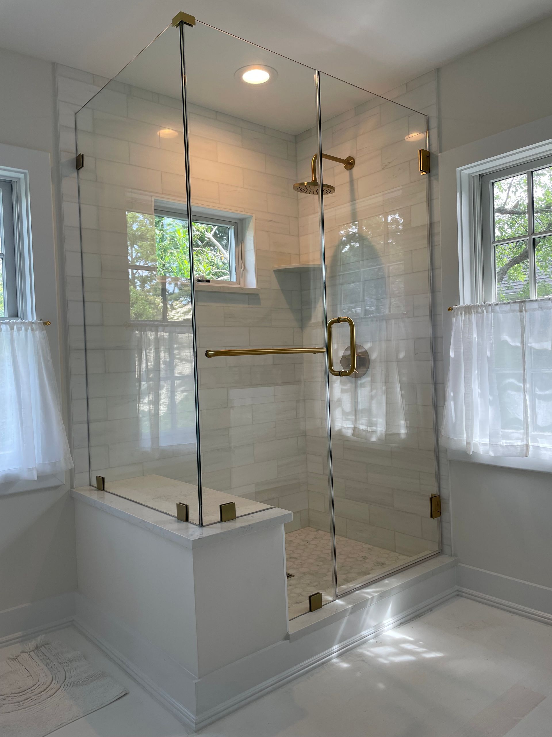 A bathroom with a glass shower door and a window.