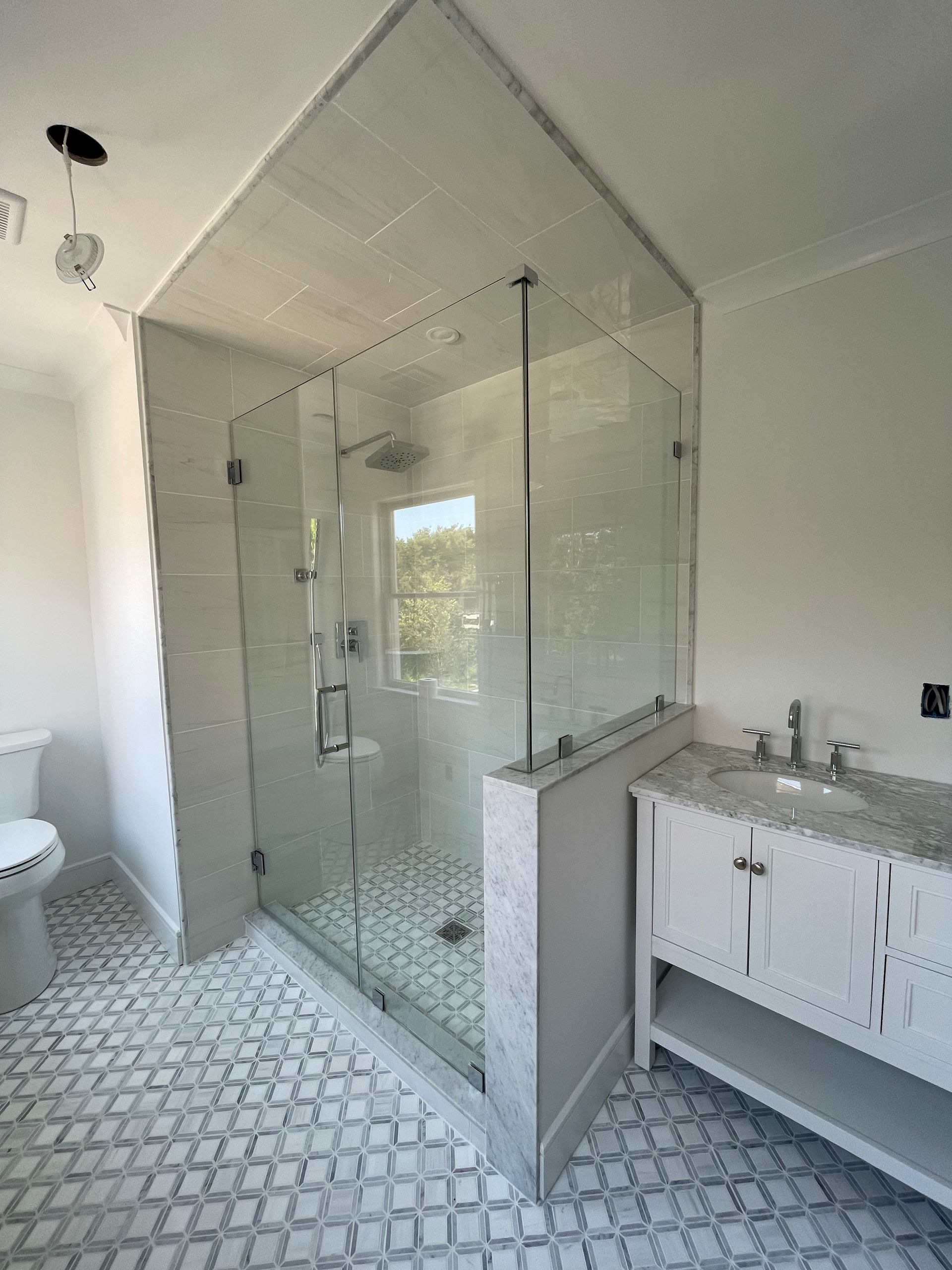 A bathroom with a walk in shower , sink and toilet.