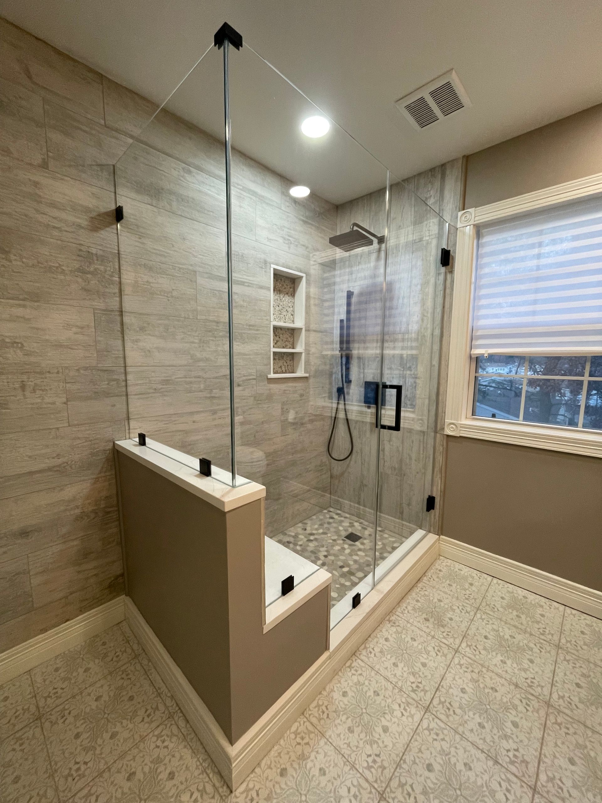 A bathroom with a walk in shower and a window.
