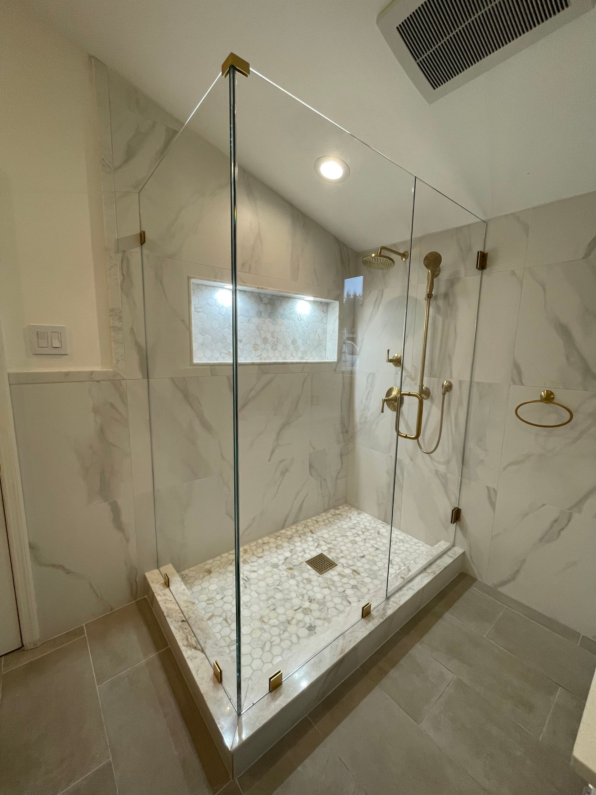 A bathroom with a walk in shower with a glass door.