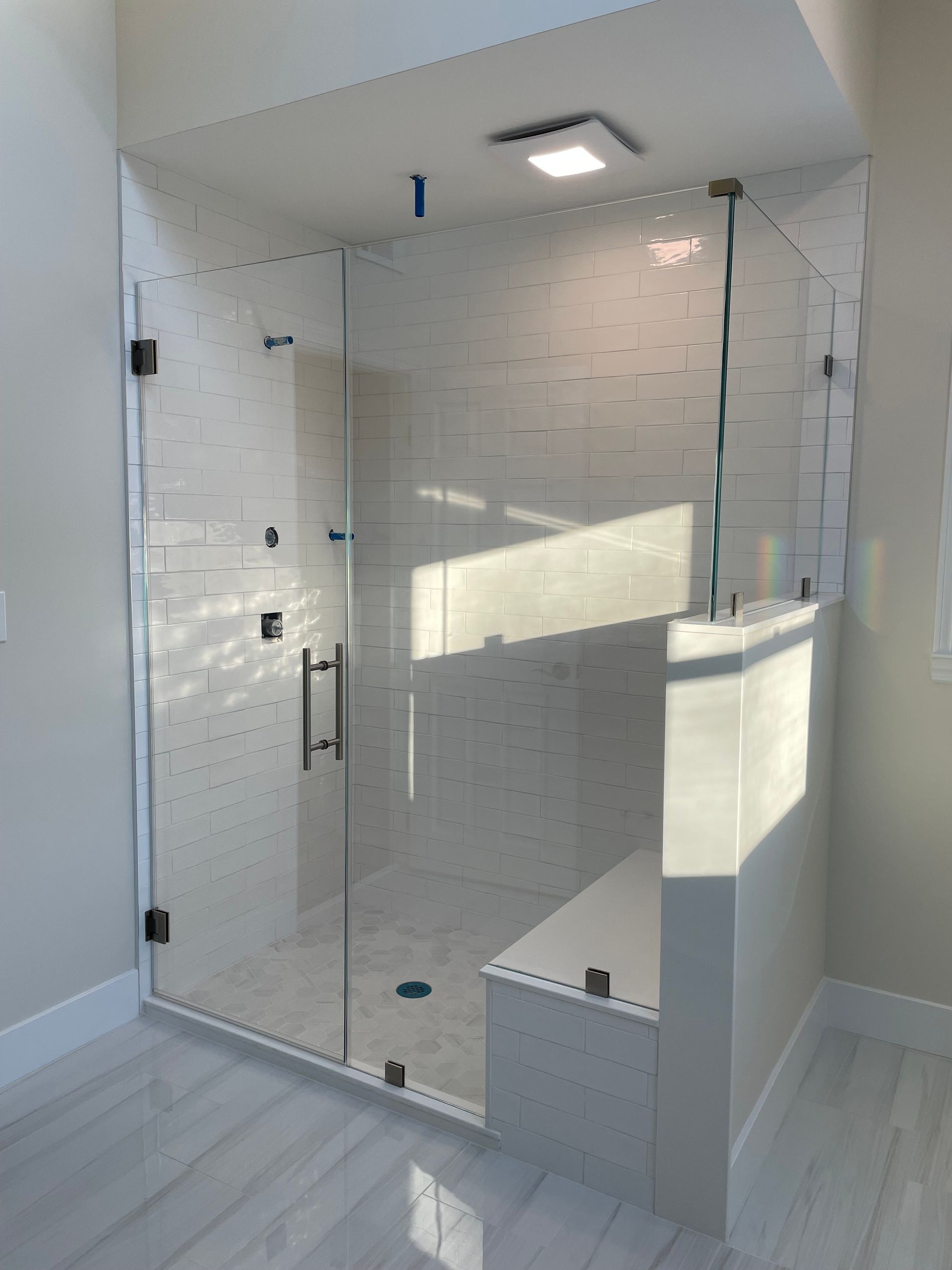 A bathroom with a walk in shower with a glass door