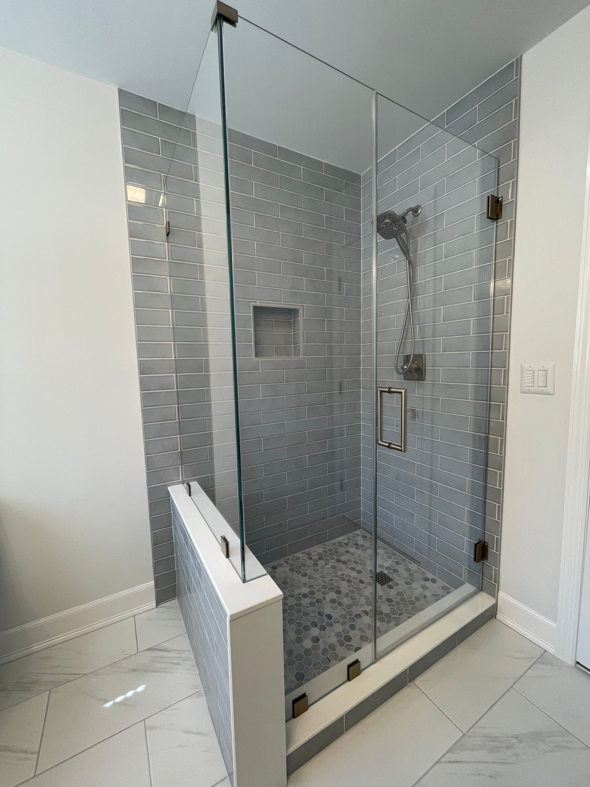 A bathroom with a walk in shower with a glass door.