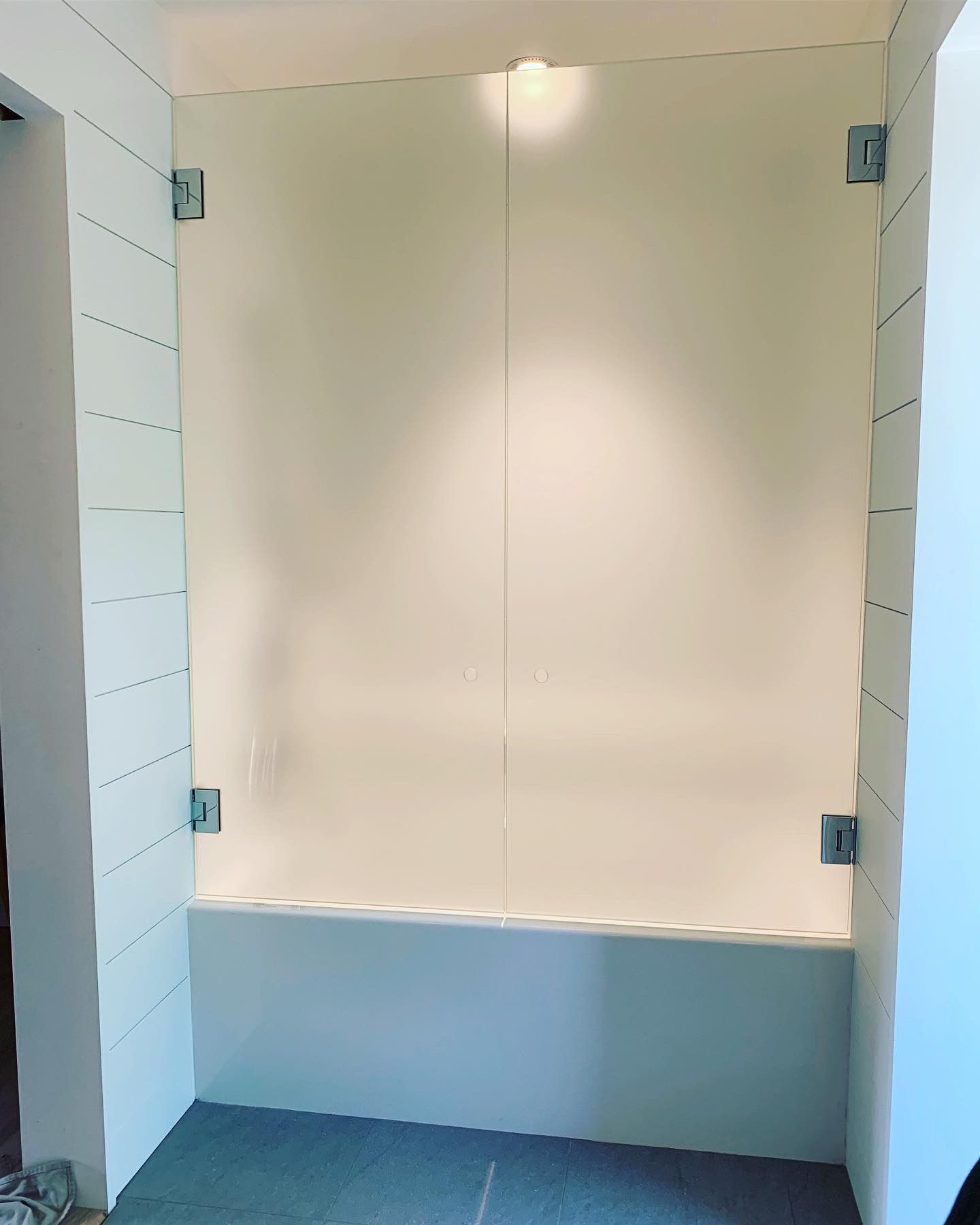 A bathroom with a bathtub and a glass shower door.