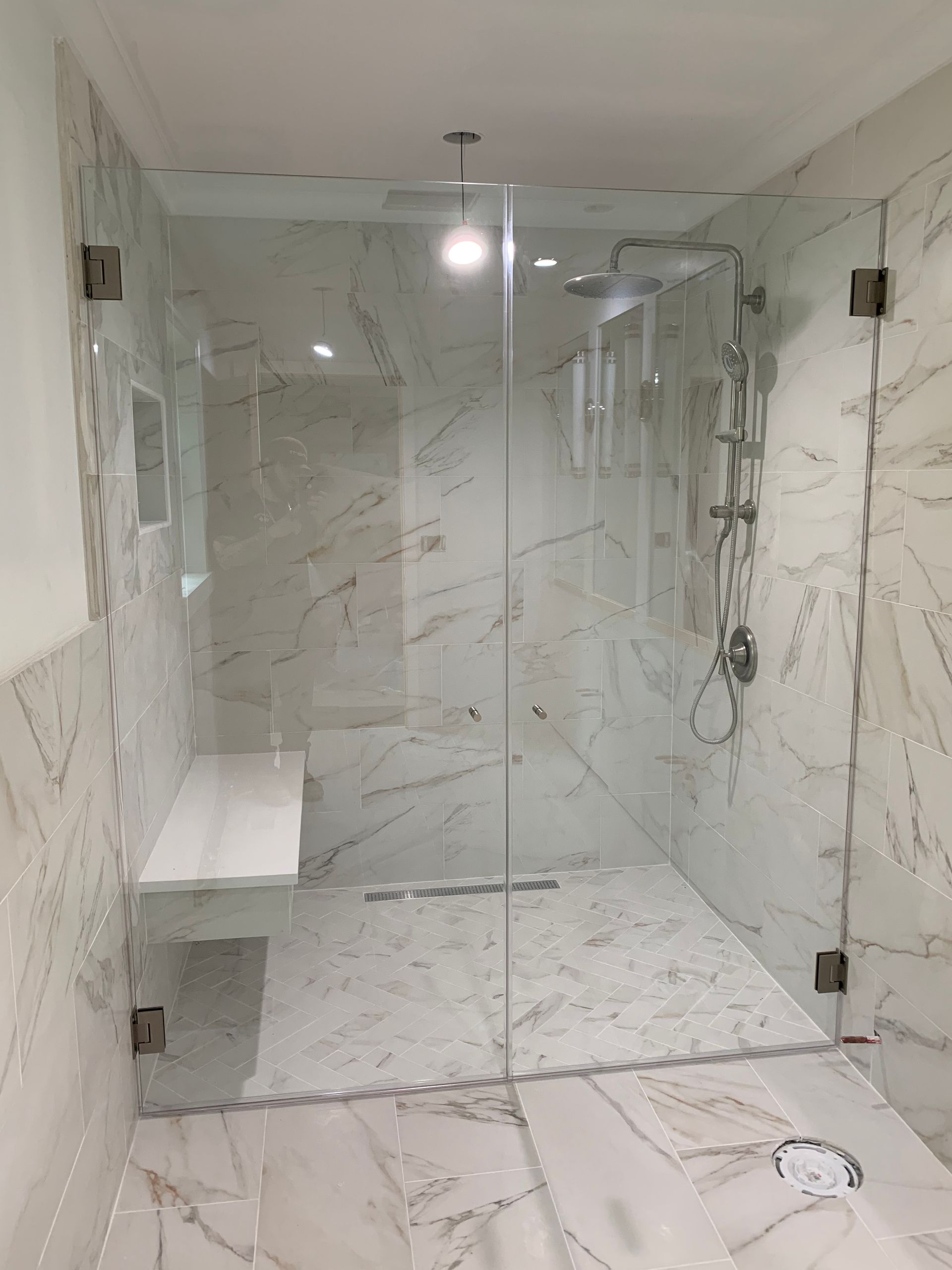 A bathroom with marble tiles and a walk in shower with a glass door.