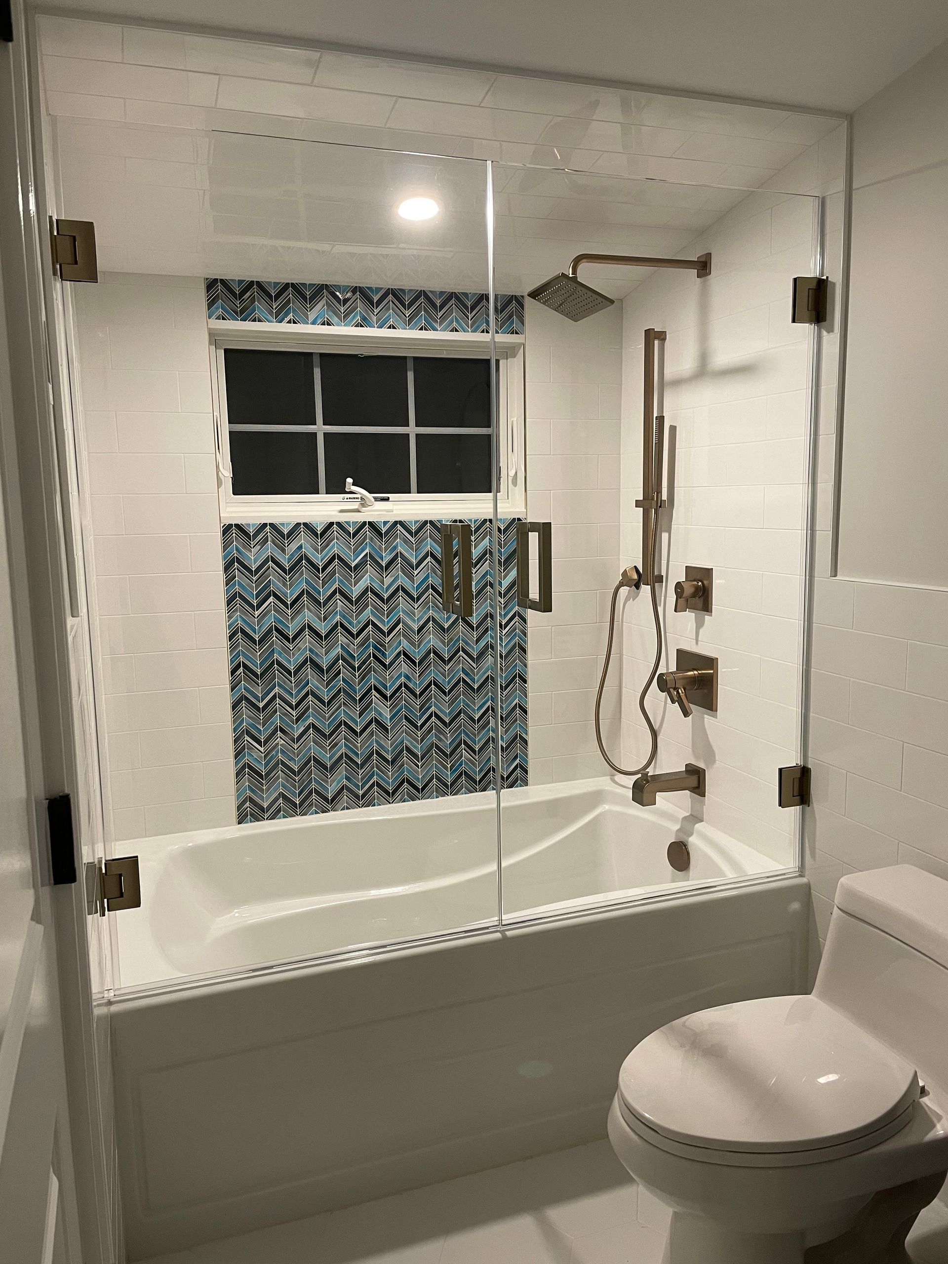 A bathroom with a tub , toilet , shower and window.