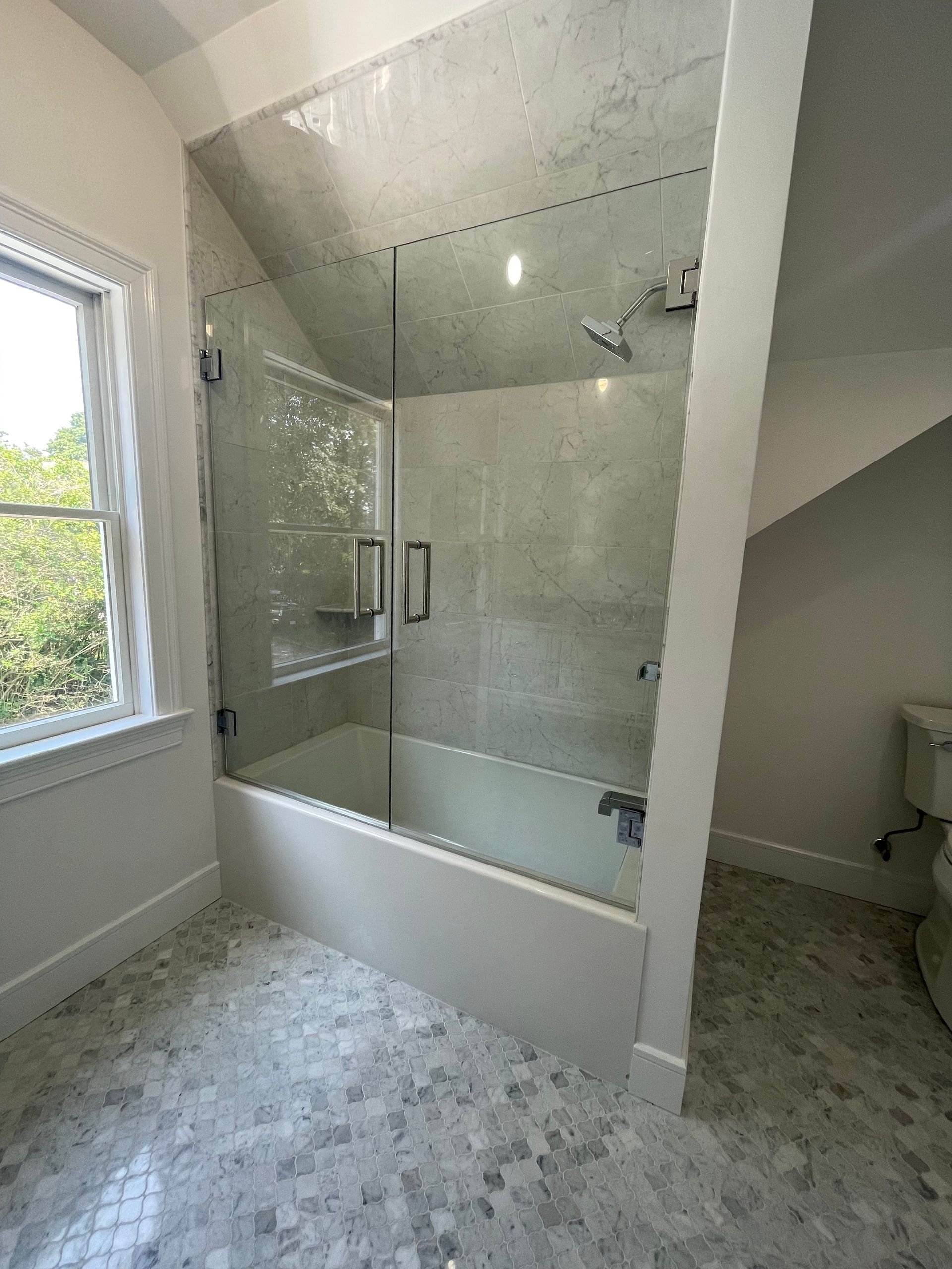 A bathroom with a bathtub and a glass shower door.