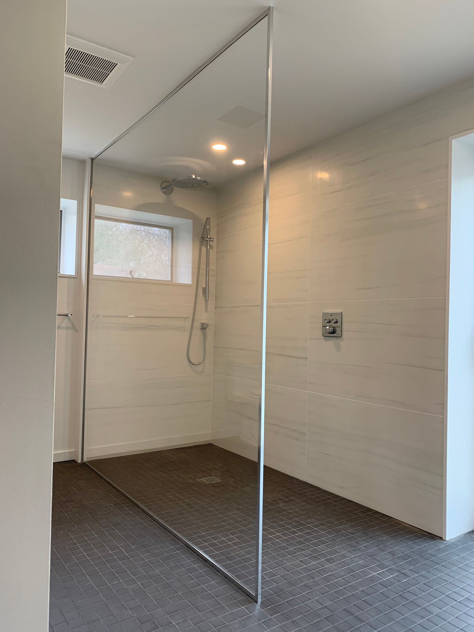 A bathroom with a walk in shower and a window.