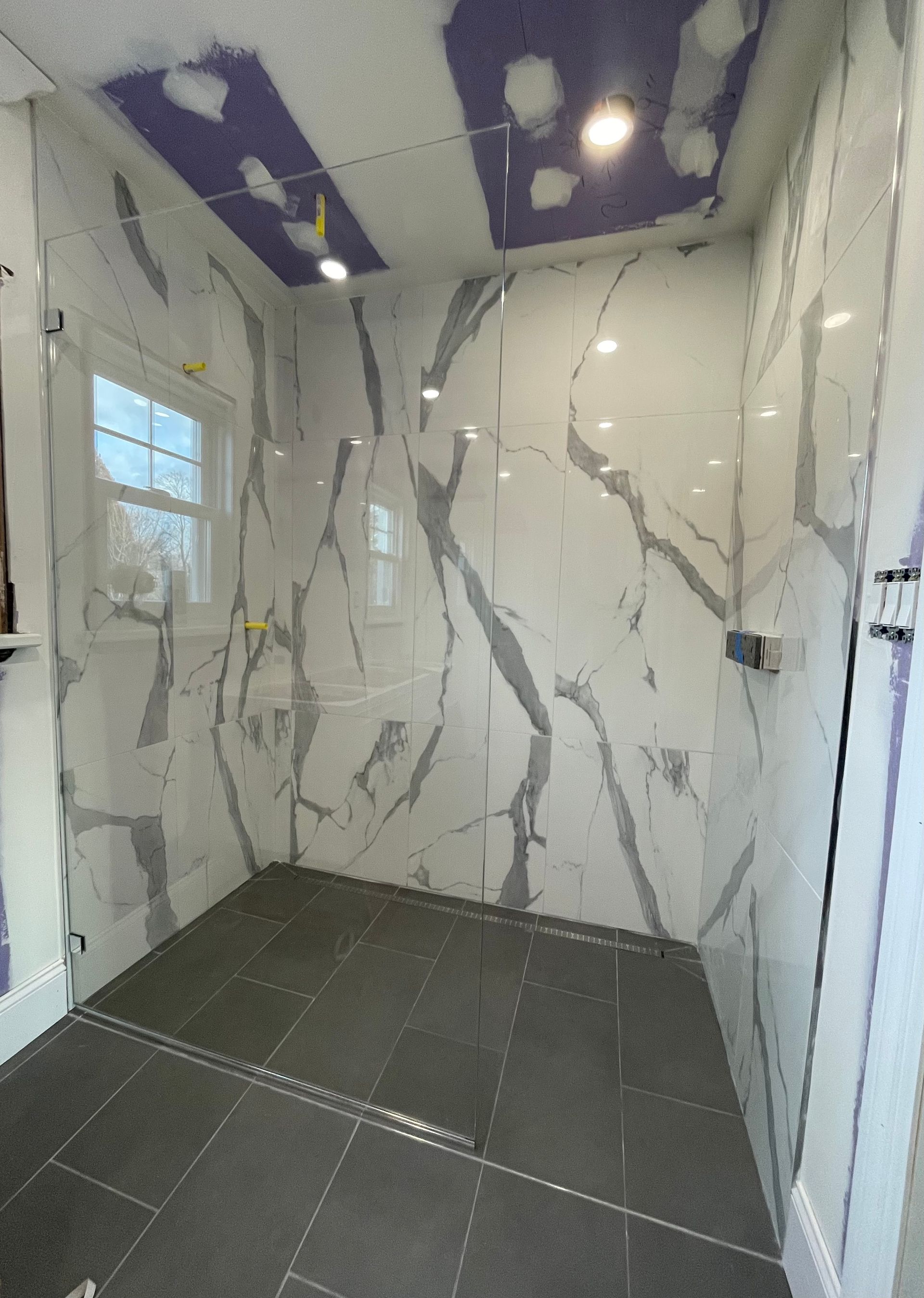 A bathroom with a walk in shower and a purple ceiling.