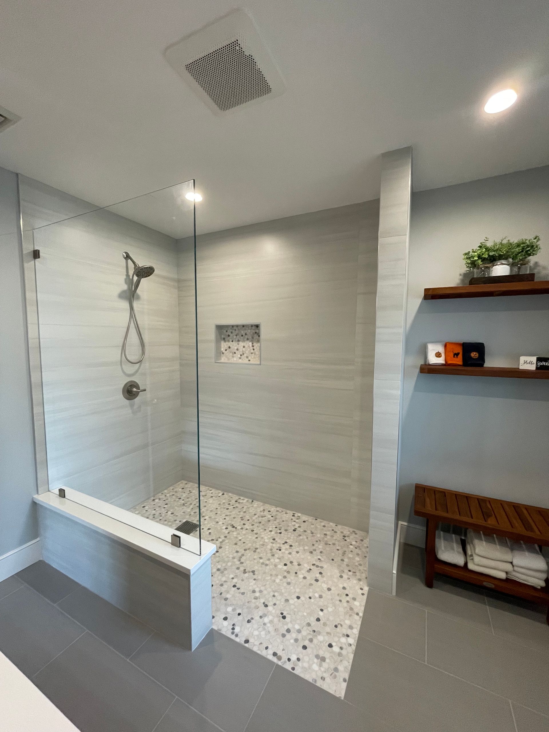 A bathroom with a walk in shower with a glass door