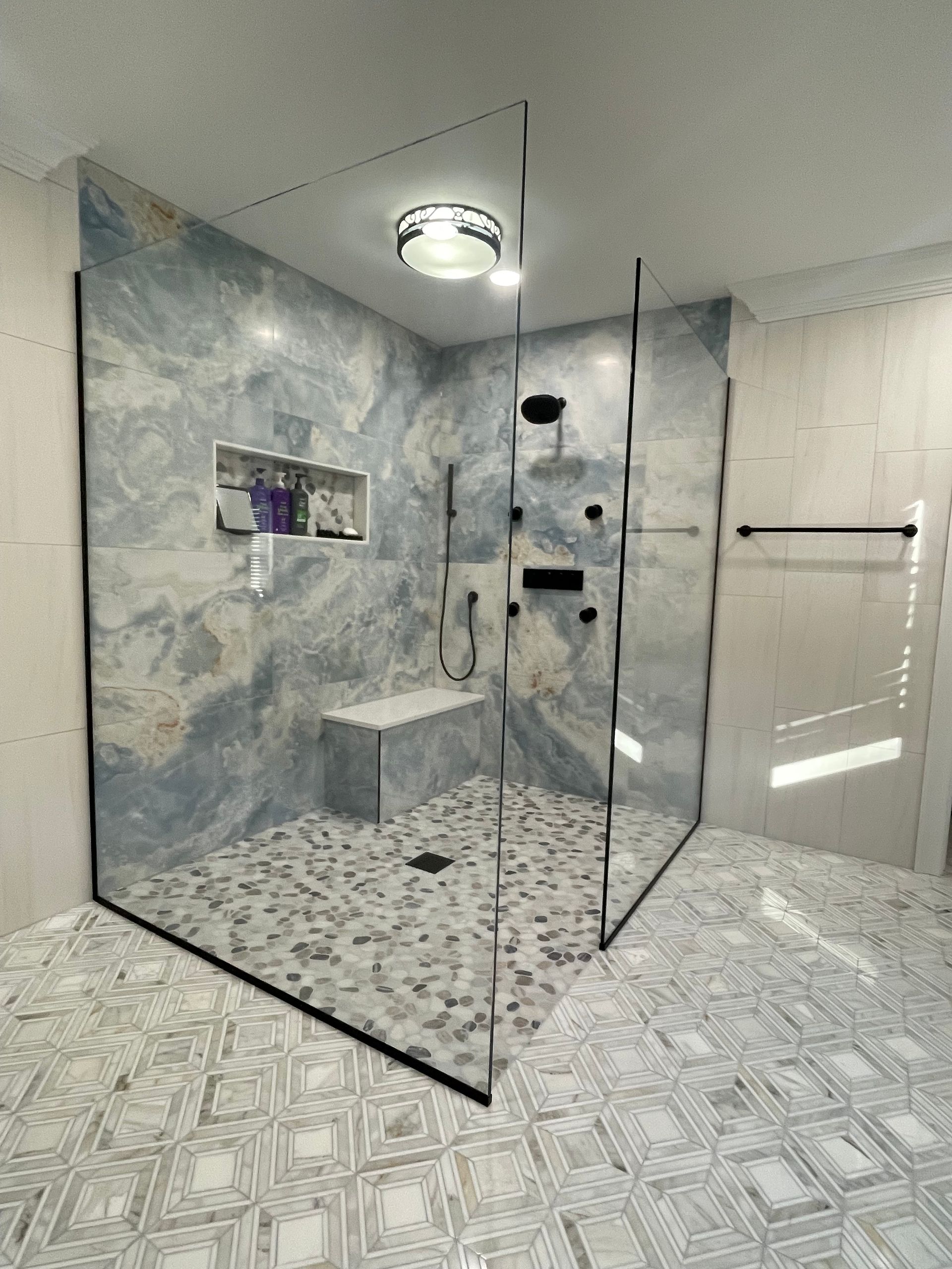 A bathroom with a walk in shower with a glass door.