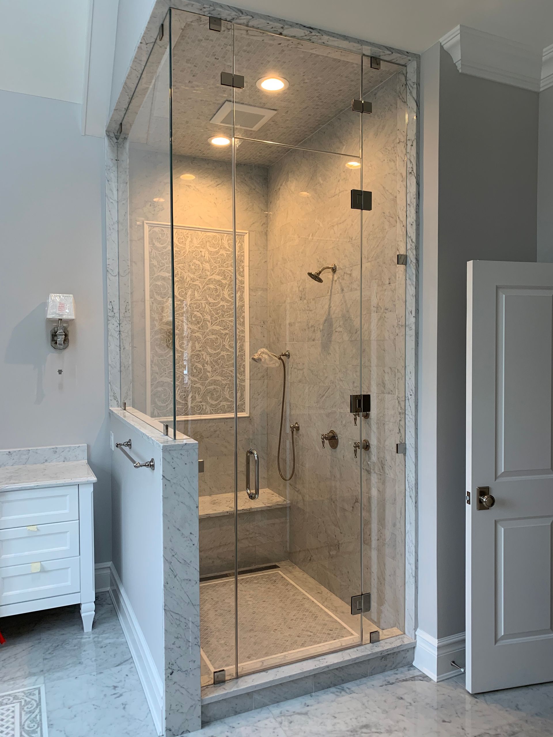 A bathroom with a walk in shower with a glass door.