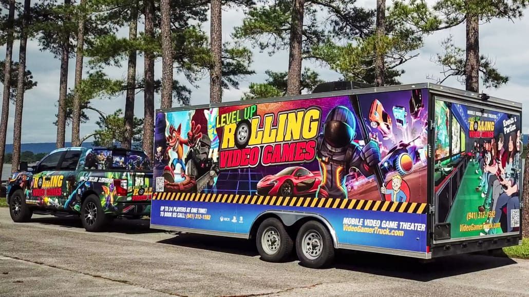 Truck towing trailer, both with colorful game-themed graphics.