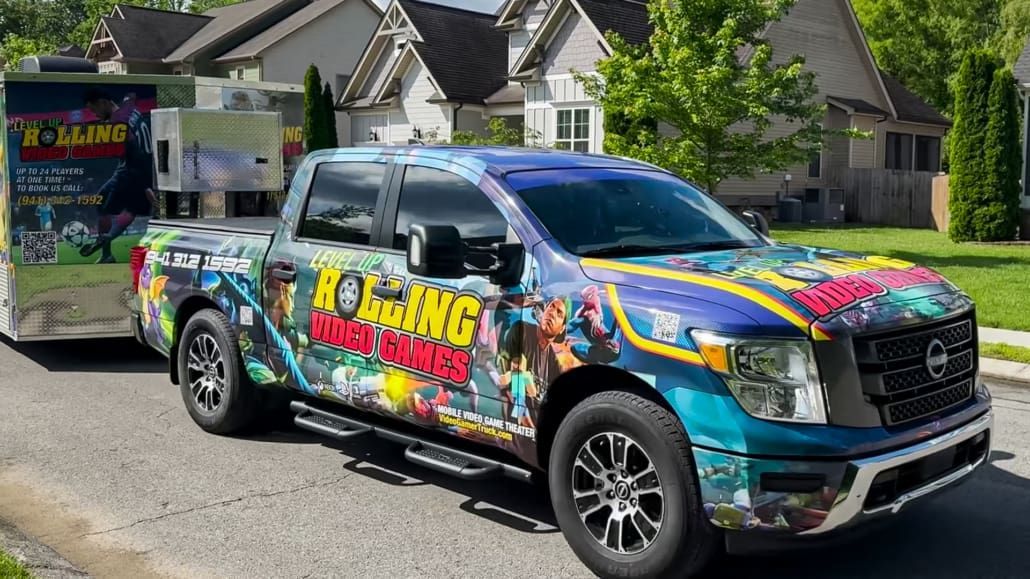 Truck with colorful wrap towing a trailer. In a residential area on a sunny day. 