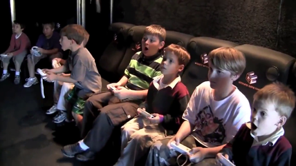 Boys playing video games, seated together with controllers, focused and engaged, indoors.