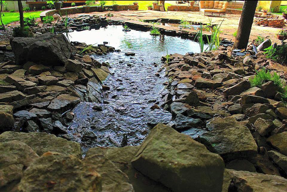 Rocky stream flowing into a small pond in a garden setting
