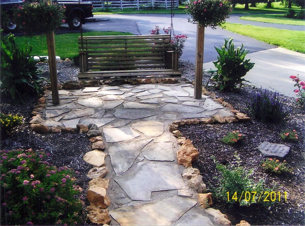 Stone walkway leading to a wooden gate in a landscaped front yard