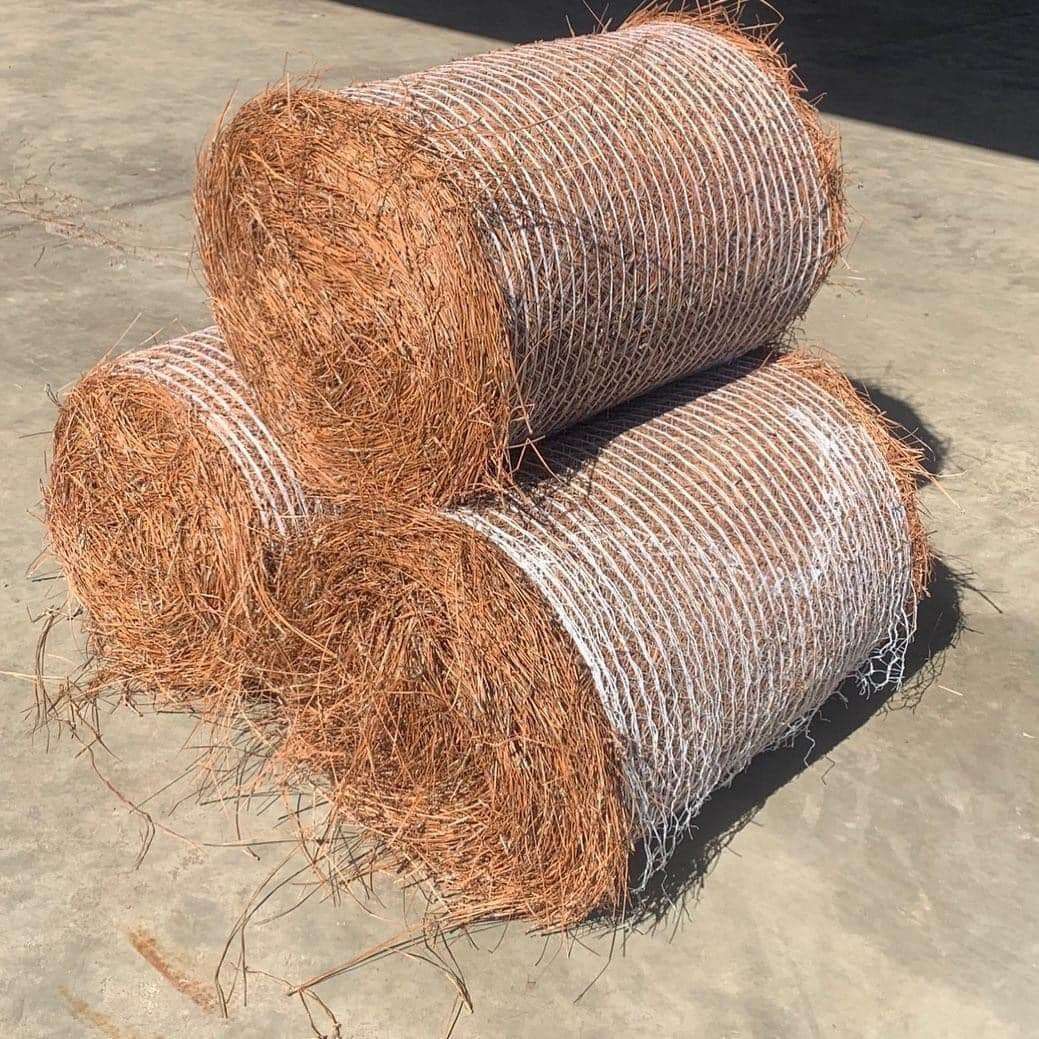 Three rolls of rusty wire mesh stacked on a concrete surface.