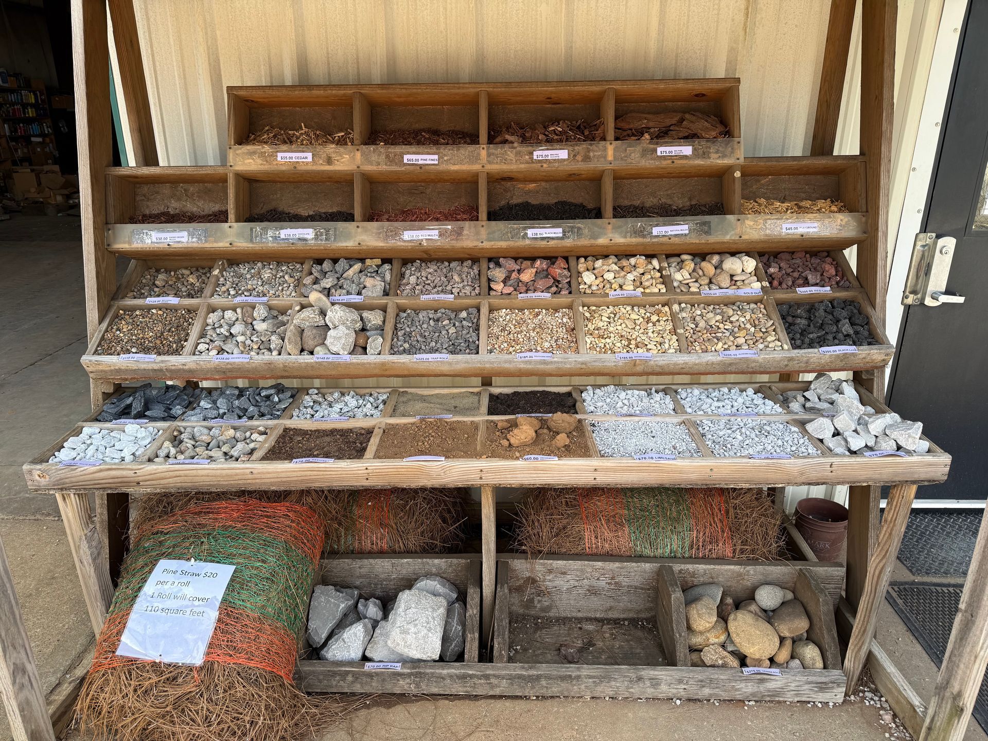 Wooden display shelf filled with small bags of assorted rocks and pebbles in an indoor shop.