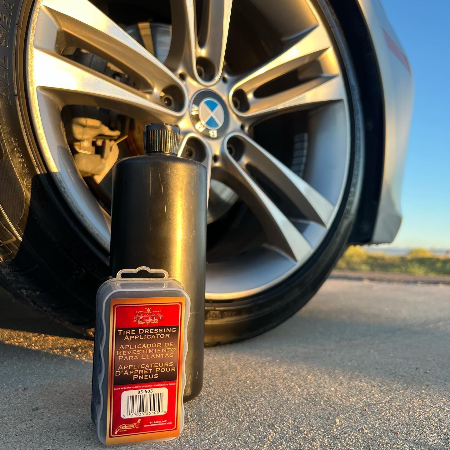 Black bottle and applicator in front of a BMW rim and tire.