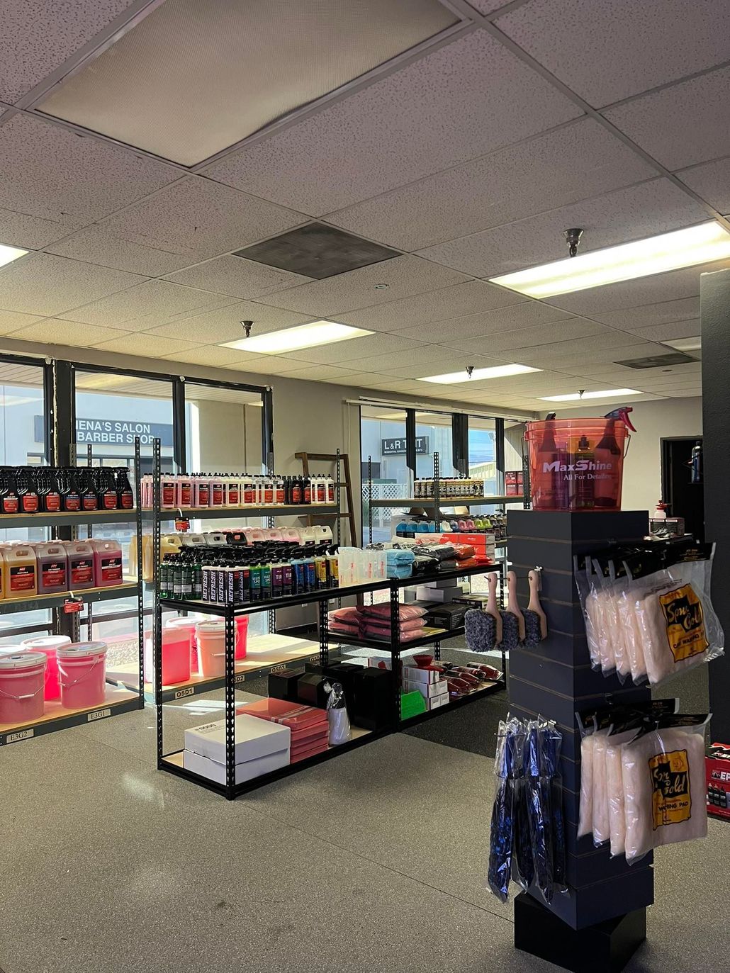 Interior of a store, featuring shelves of products, lights, and a gray speckled floor.