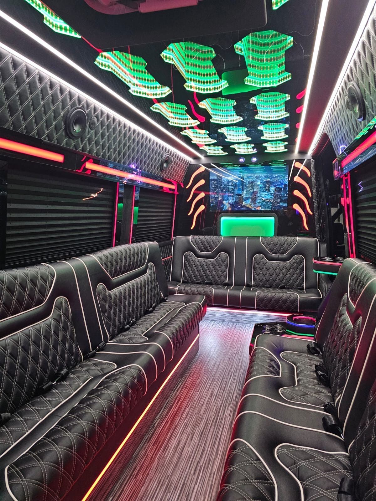 Luxury party bus interior with black tufted seats, LED ceiling lights, and neon accents