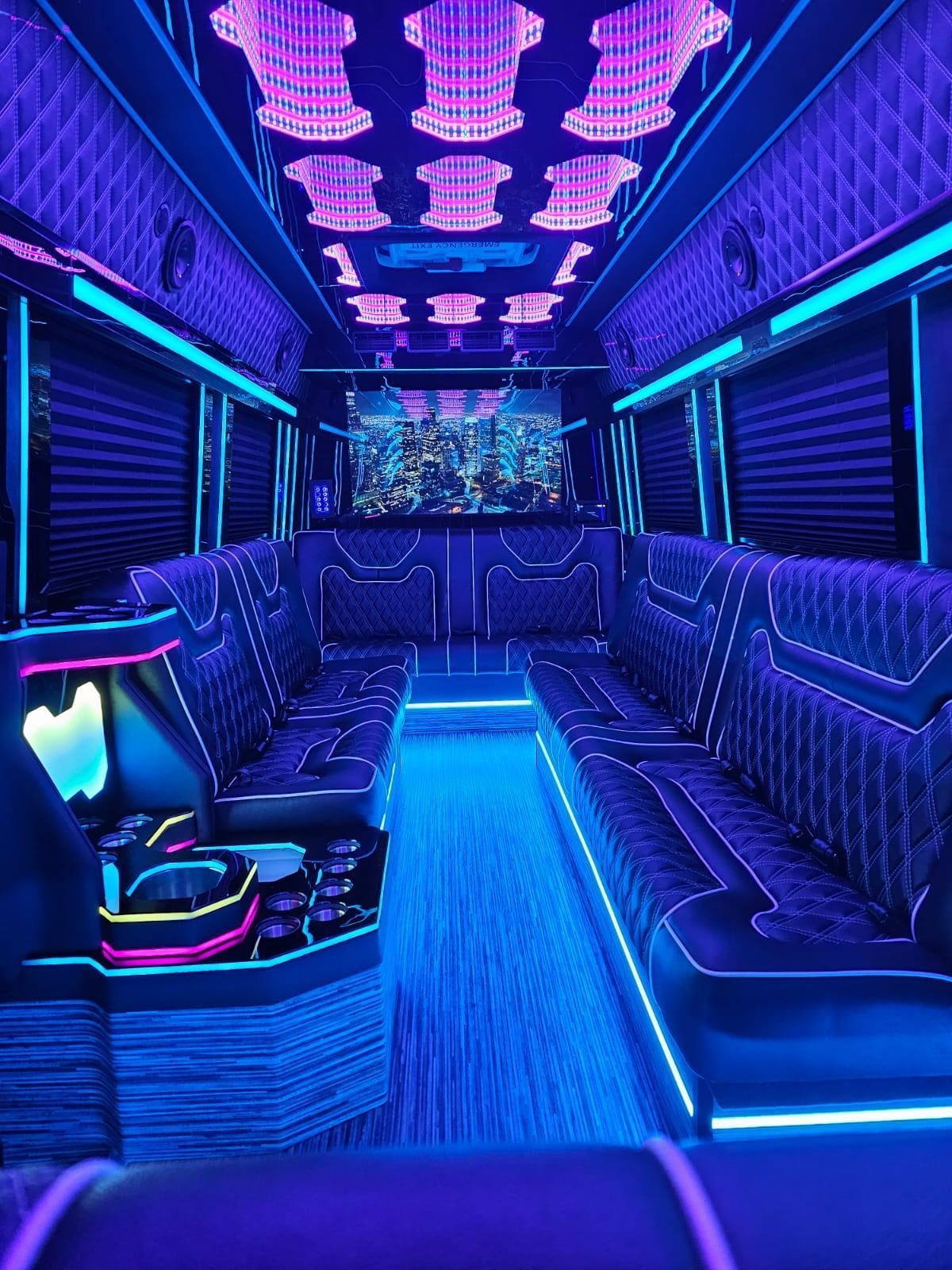 Neon-lit party bus interior with blue and purple lights, lounge seats, and a central aisle