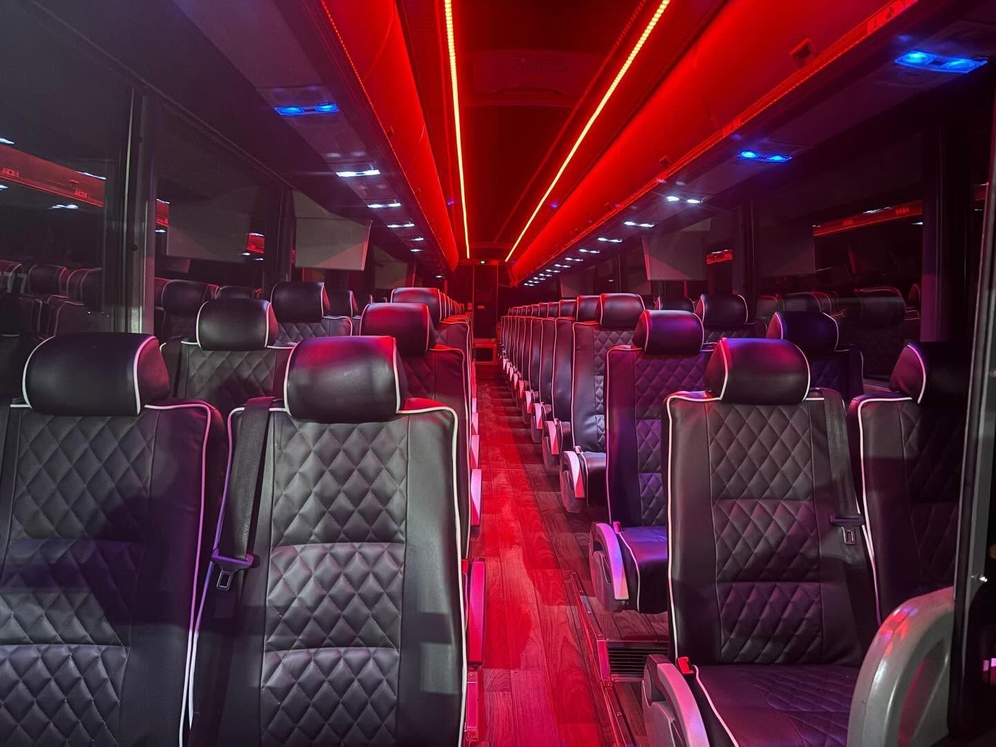 Empty bus interior with rows of black seats and red LED ceiling lights