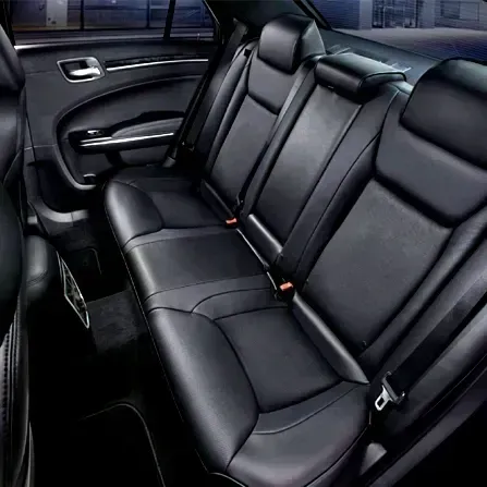 Black leather car back seat with three headrests and seat belts in a sedan interior
