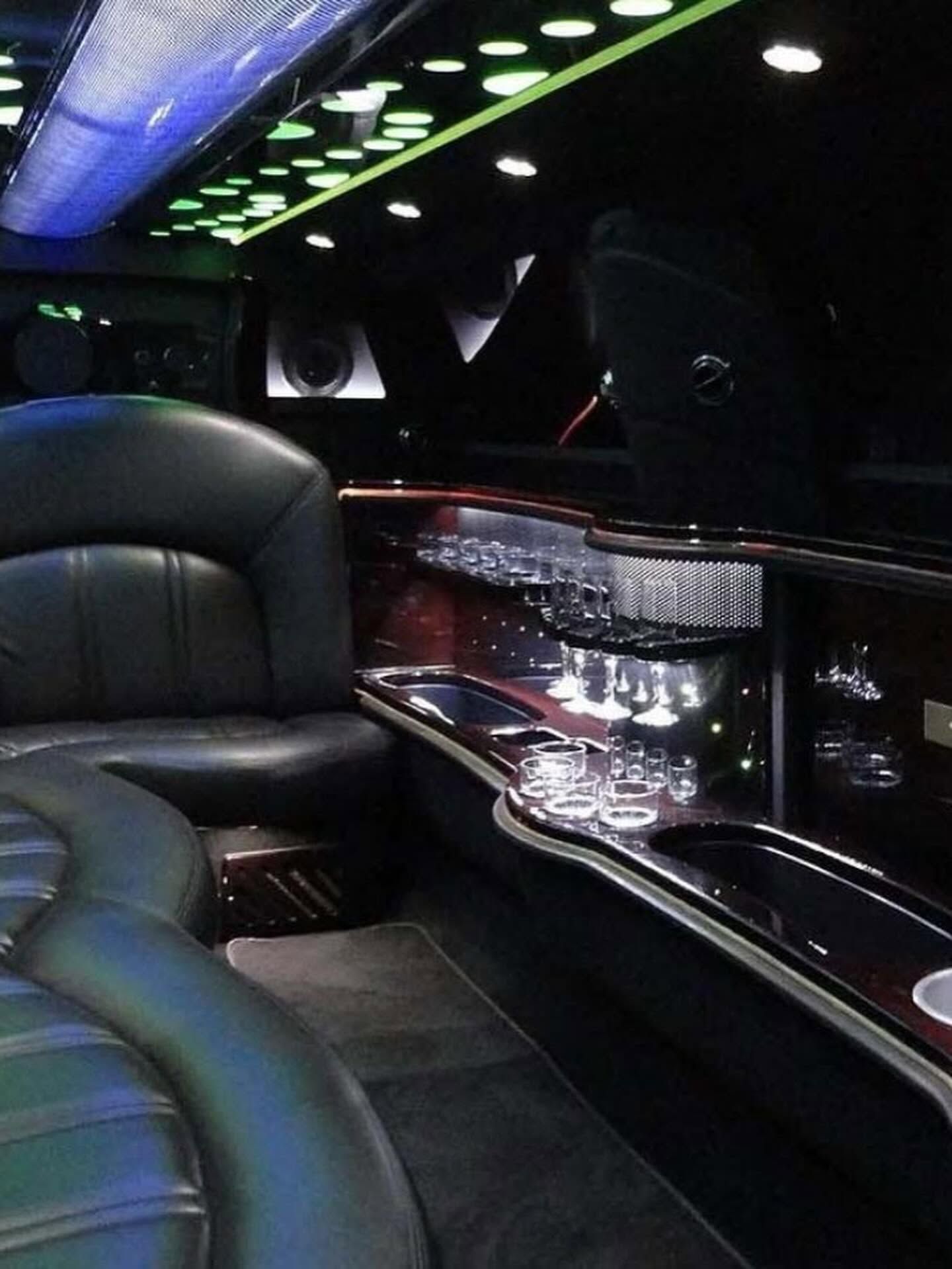 Luxury limousine interior with black leather seats, chrome trim, and ceiling lights